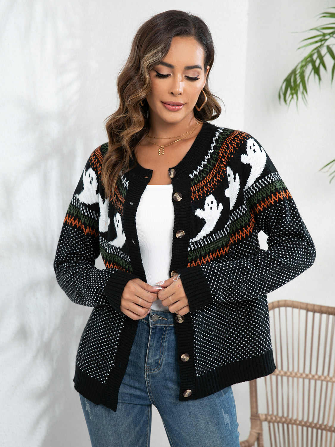 A woman wears a black button-up cardigan with white ghost patterns and colorful accents.