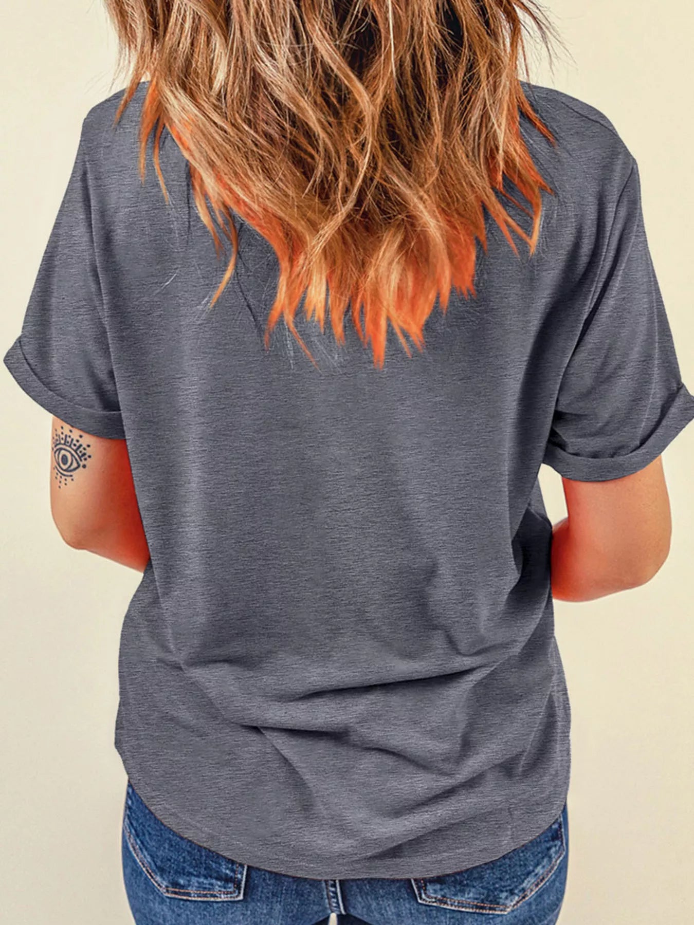Back view of a woman wearing a gray short-sleeved t-shirt and blue jeans.