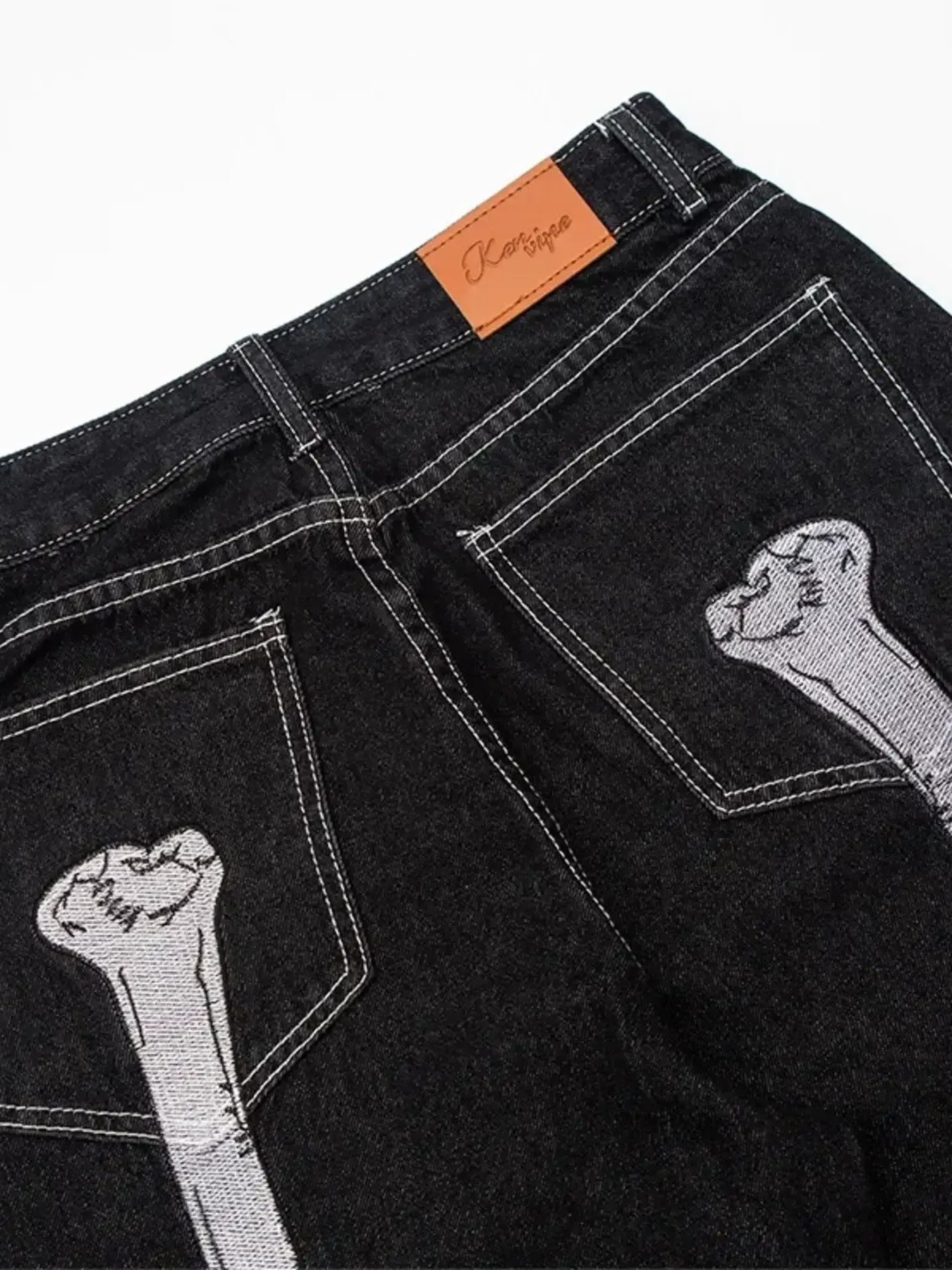 Black straight-leg jeans with white stitching and bone embroidery on the back pockets.
