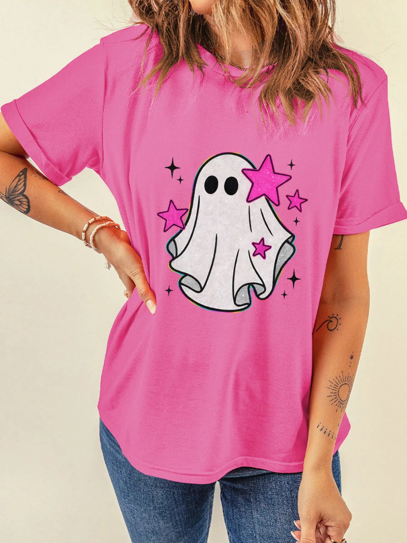 A woman wears a pink t-shirt with a ghost and pink stars graphic.