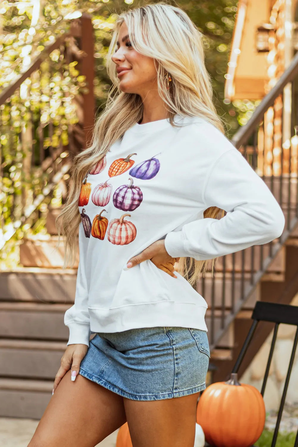 Pumpkin Graphic Long Sleeve Sweatshirt worn by a woman with long blonde hair and a denim skirt.