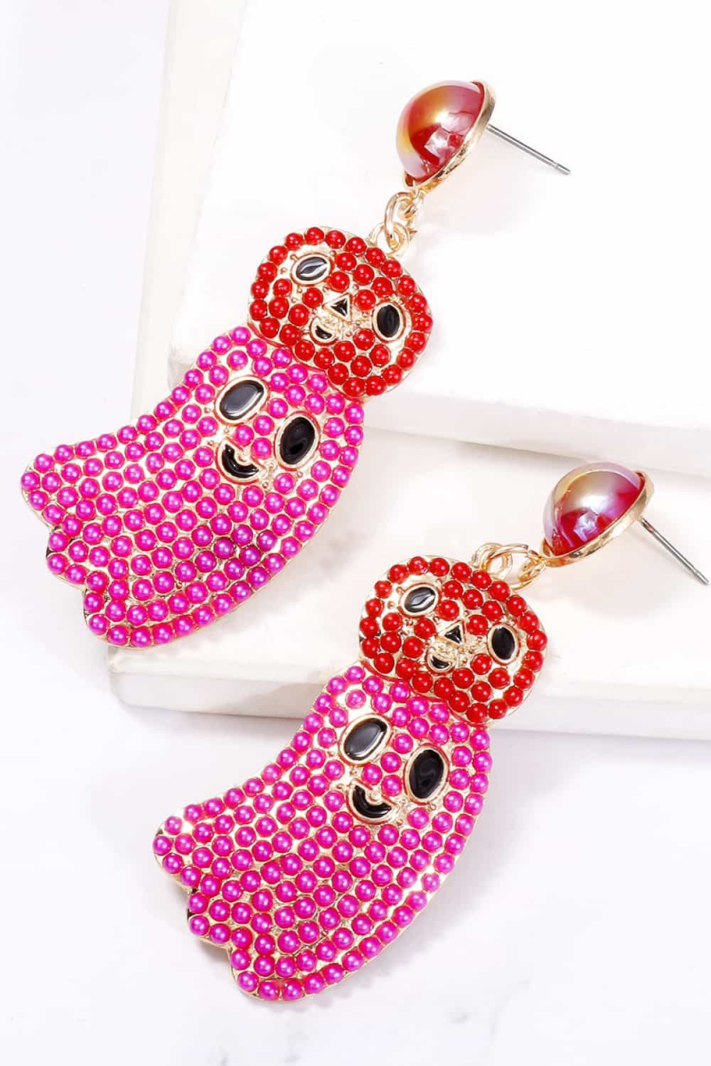 Two pink and red ghost-shaped dangle earrings with black facial features.