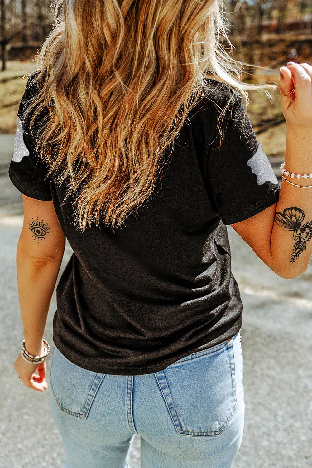 A woman from behind wears a black short-sleeve t-shirt with glitter ghost designs.