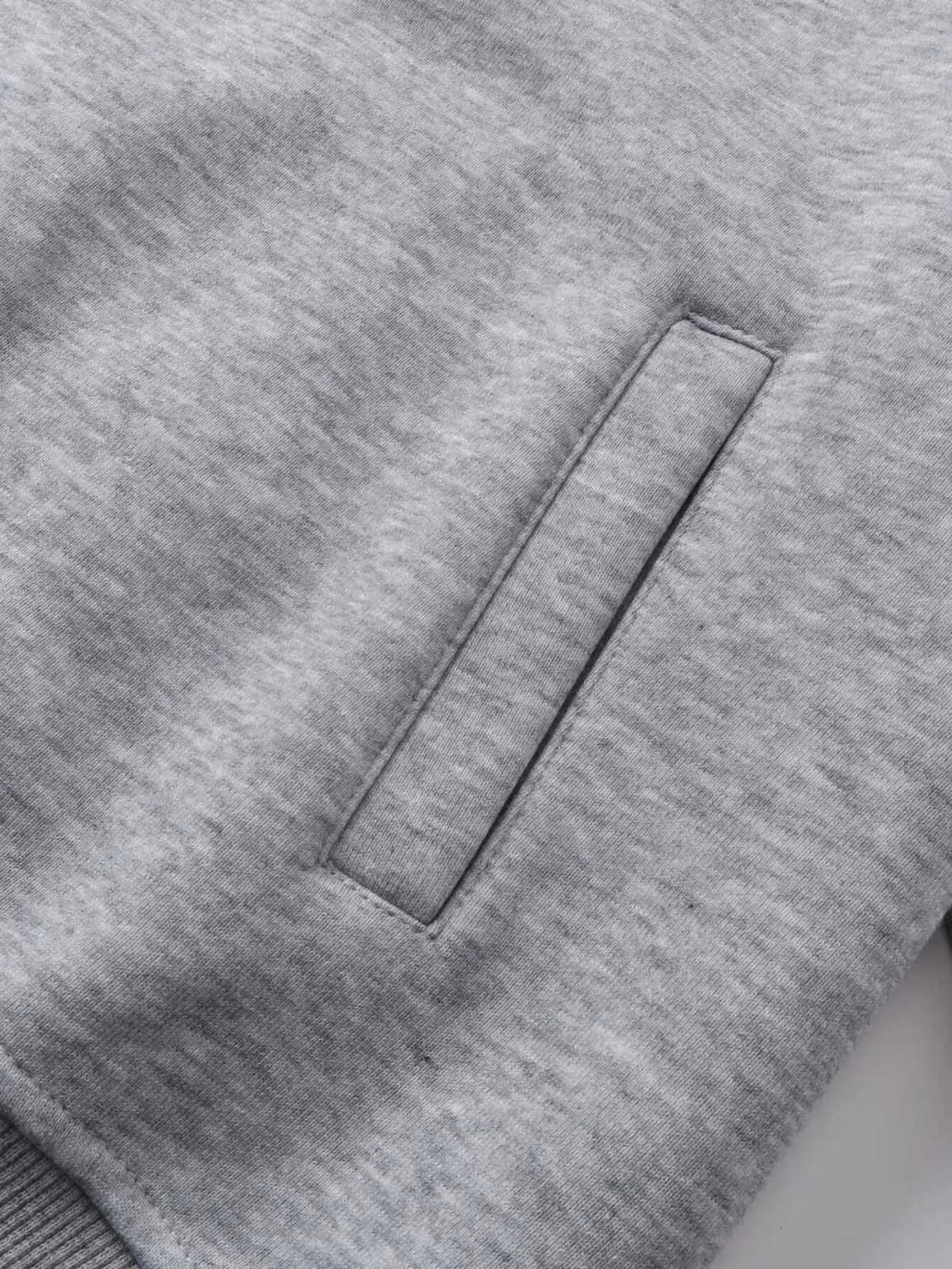 Close-up of a gray hoodie with a vertical pocket opening.