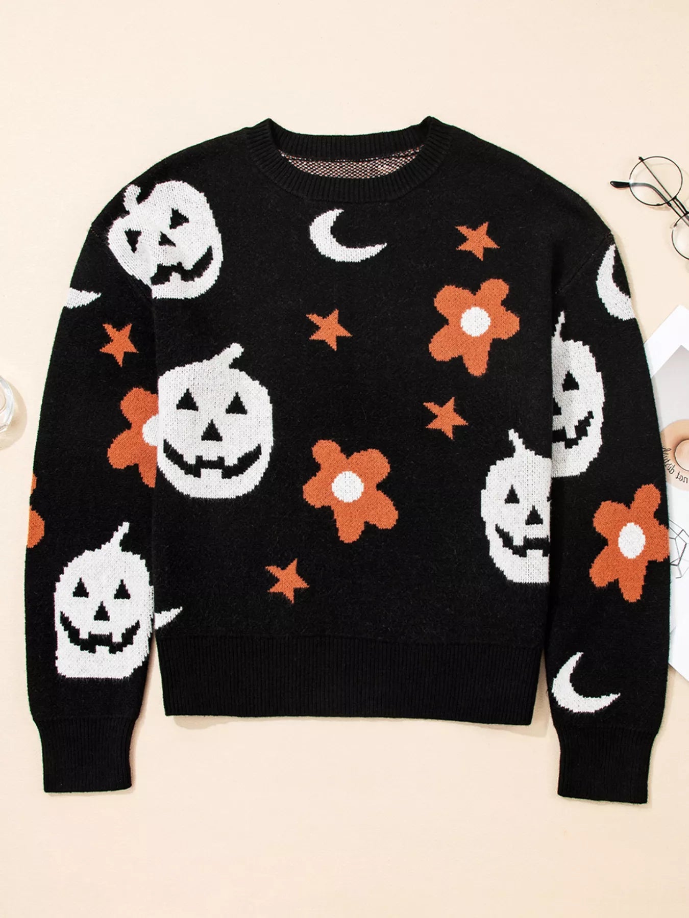 Black long-sleeve sweater with white pumpkins, orange flowers, and stars.
