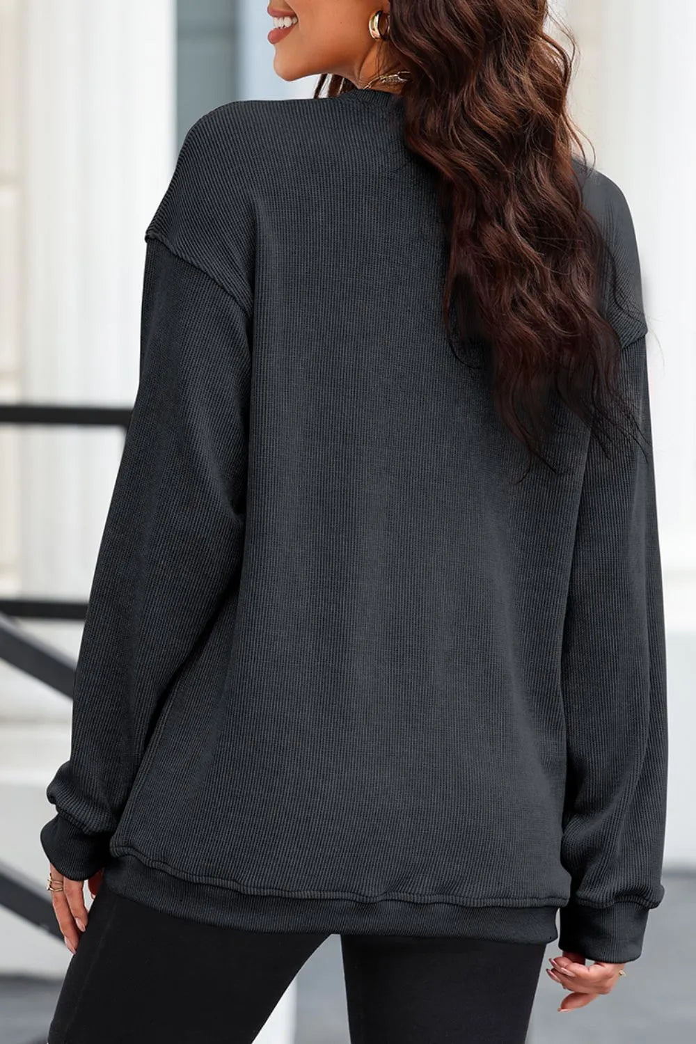 A woman from the back wearing a dark gray ribbed long-sleeve sweatshirt.