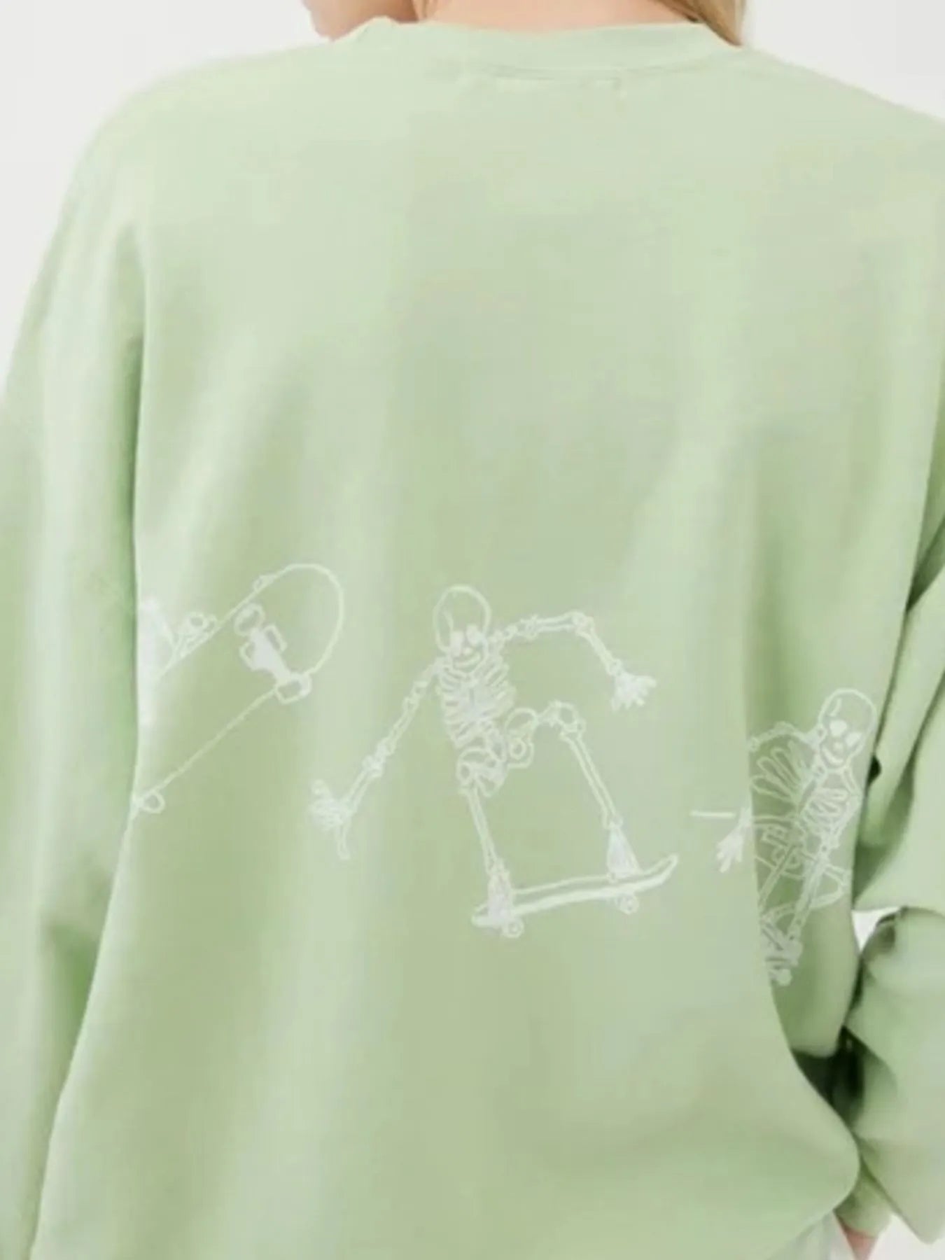 Oversized light green sweatshirt with white skeleton graphic skateboarding across the back.