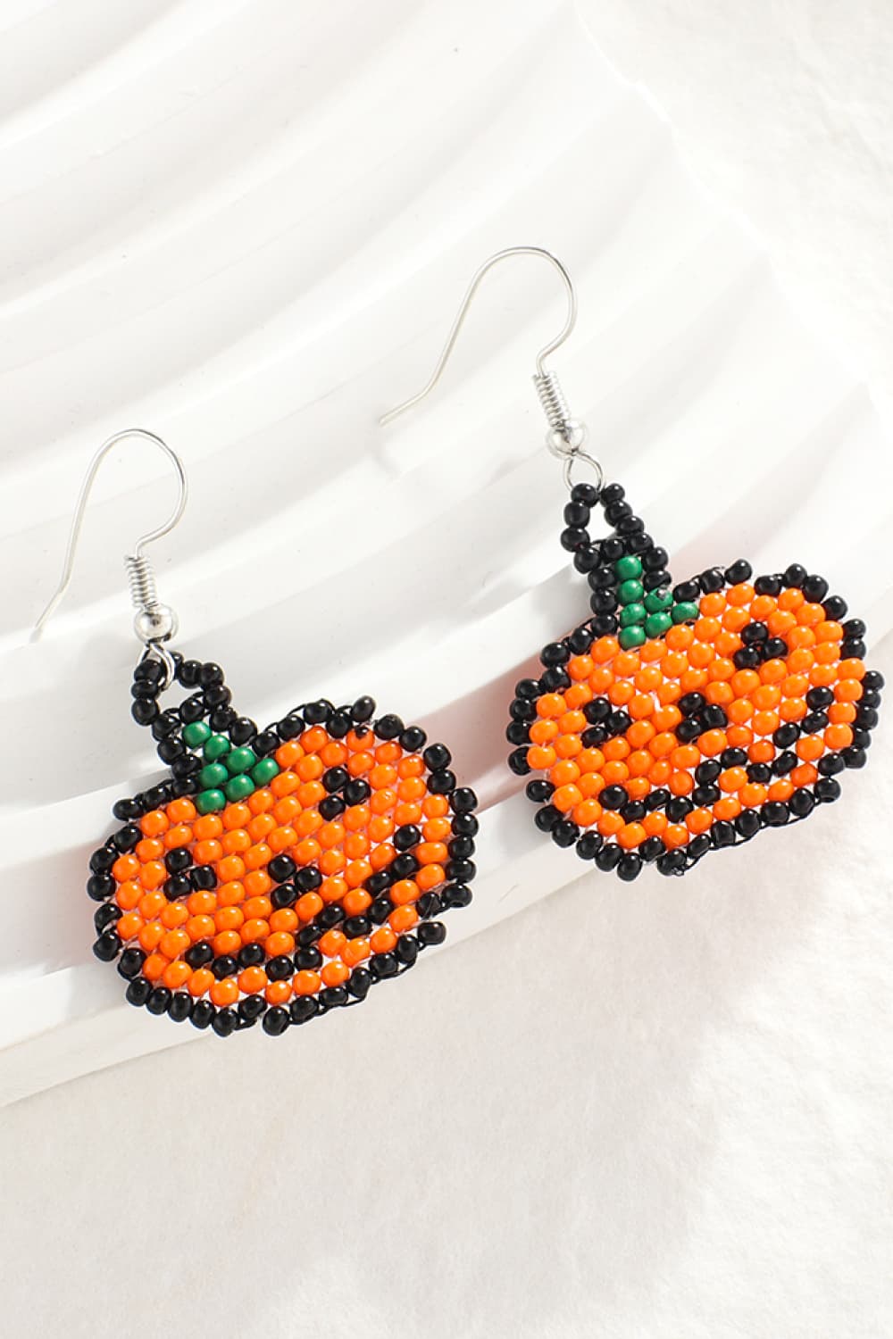 Two beaded Halloween pumpkin earrings with orange, black, and green beads.
