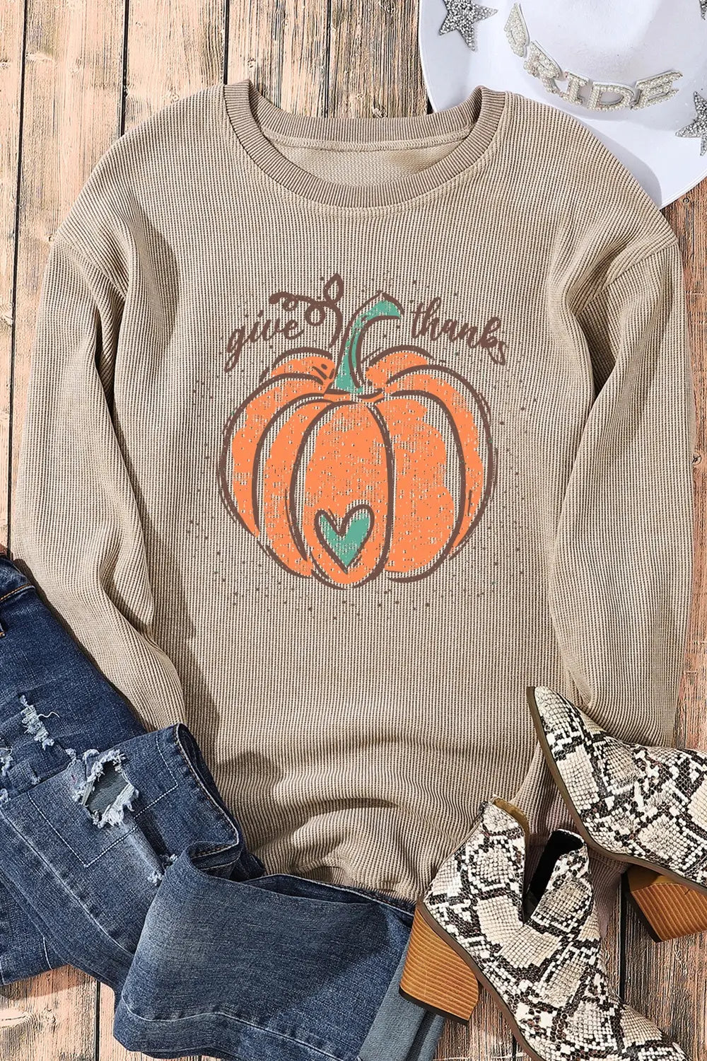 Pumpkin graphic round neck long sleeve sweatshirt with distressed jeans and snakeskin boots.