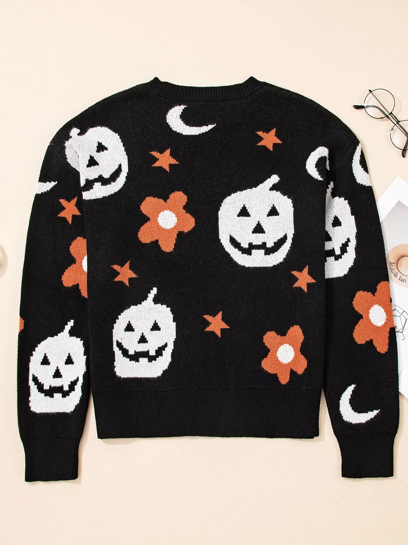 Black long-sleeve sweater with white pumpkins, orange flowers, and moons.