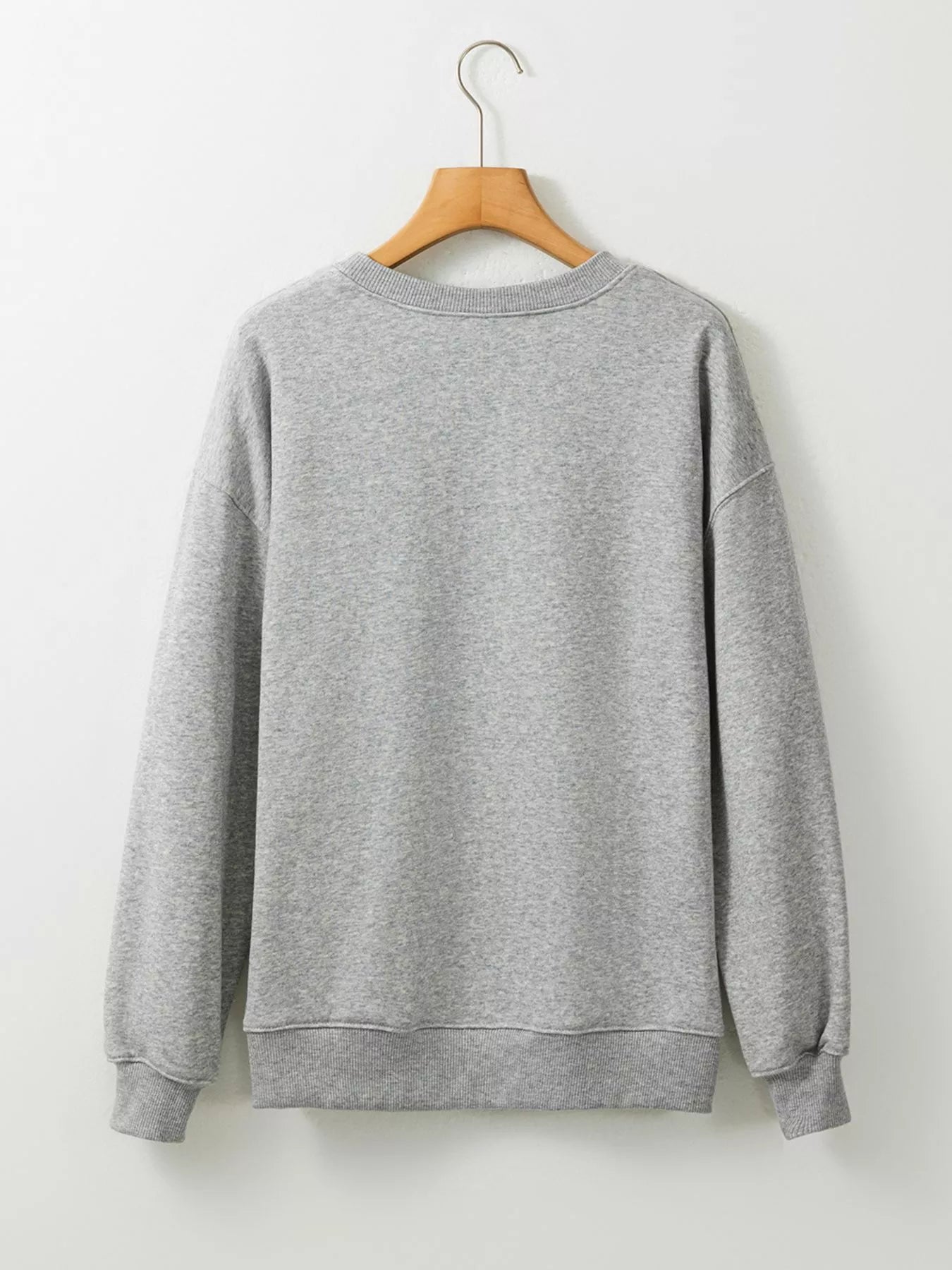 Gray long-sleeved sweatshirt with ribbed cuffs and hem, hanging on a wooden hanger.