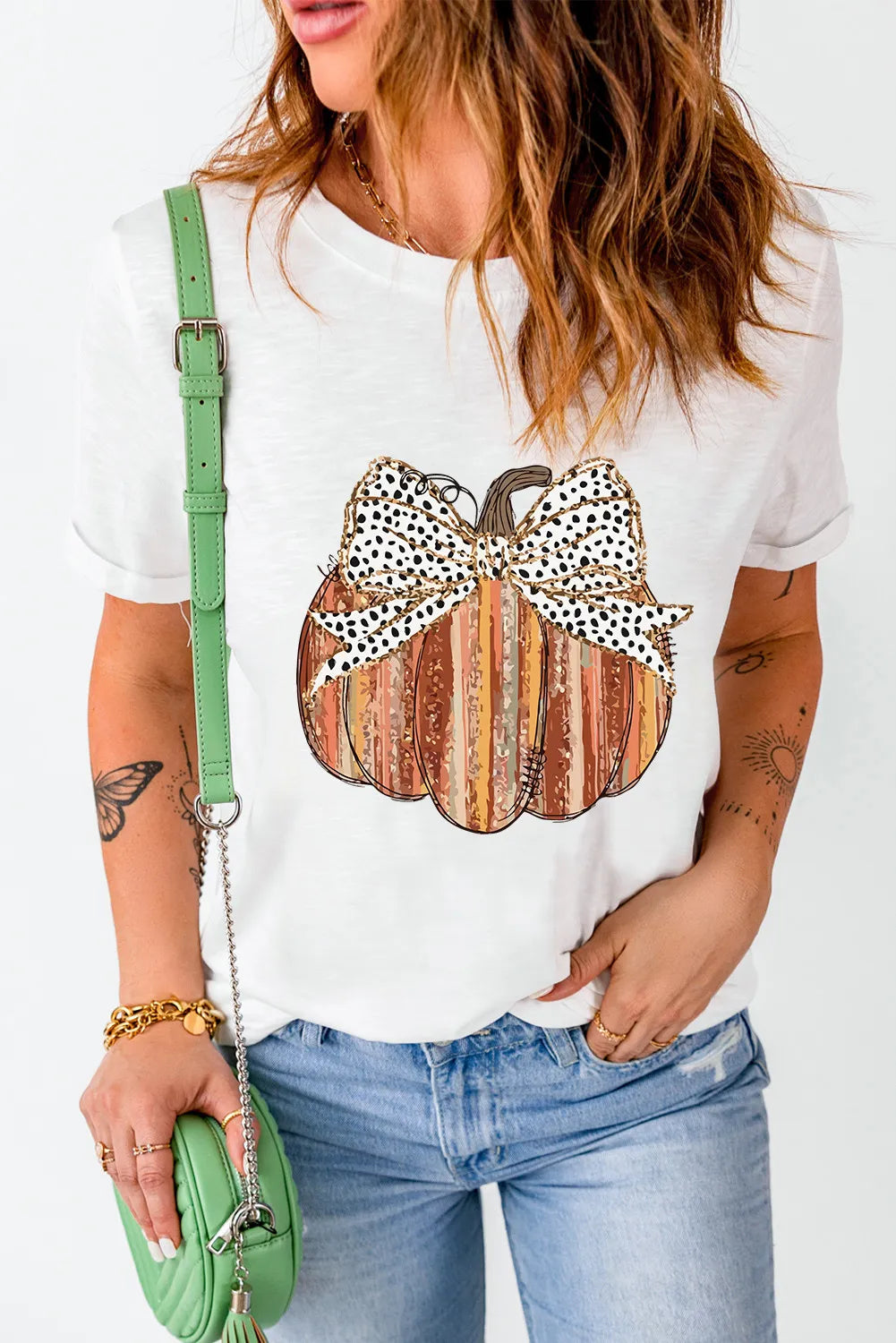 A woman wears a white short-sleeve t-shirt with a striped pumpkin and leopard print bow.