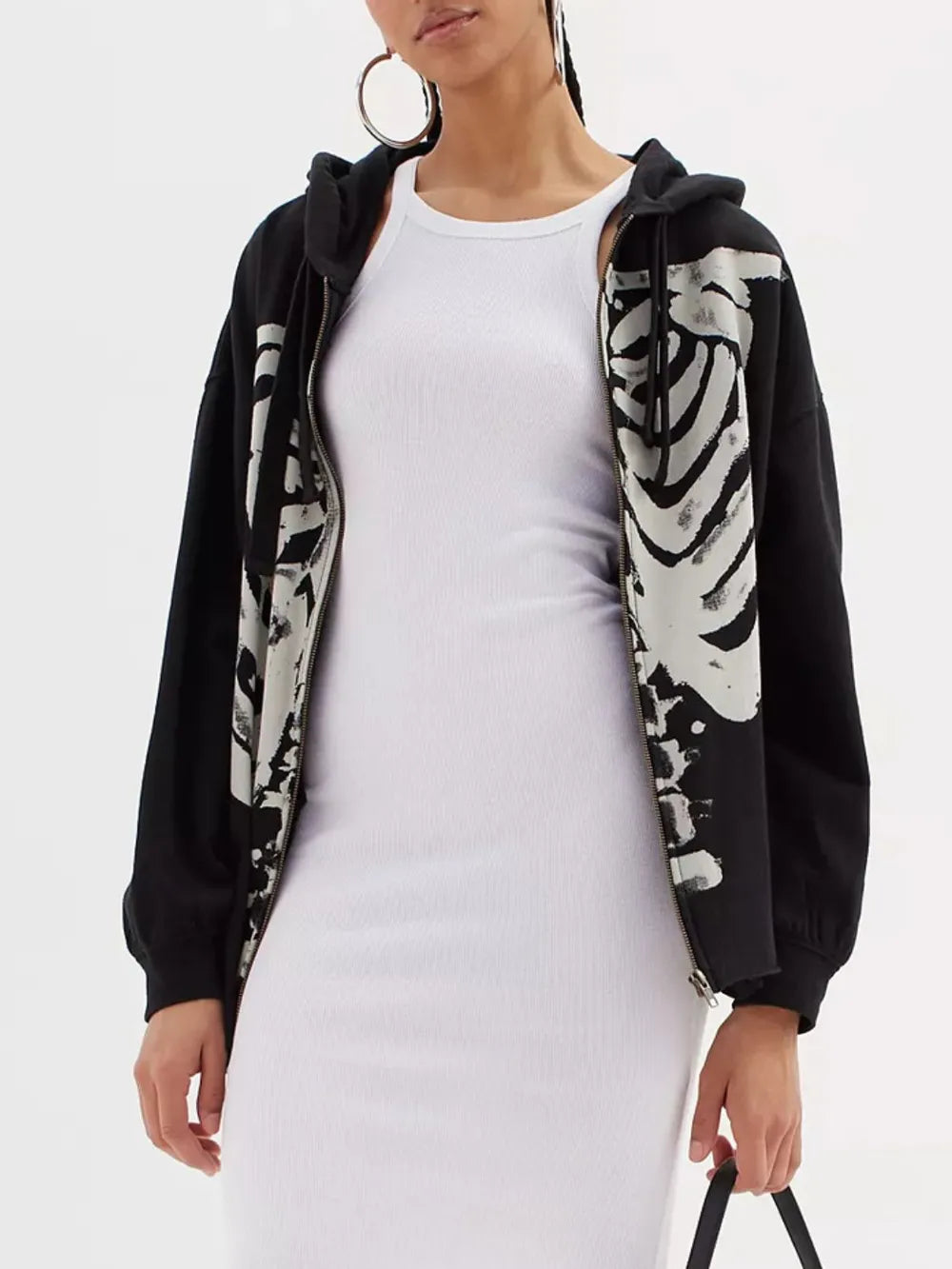 Skeleton zip-up drawstring hoodie worn over a white ribbed dress.
