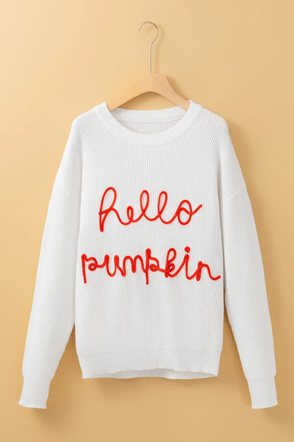 White long-sleeve sweater with "hello pumpkin" embroidered in red.
