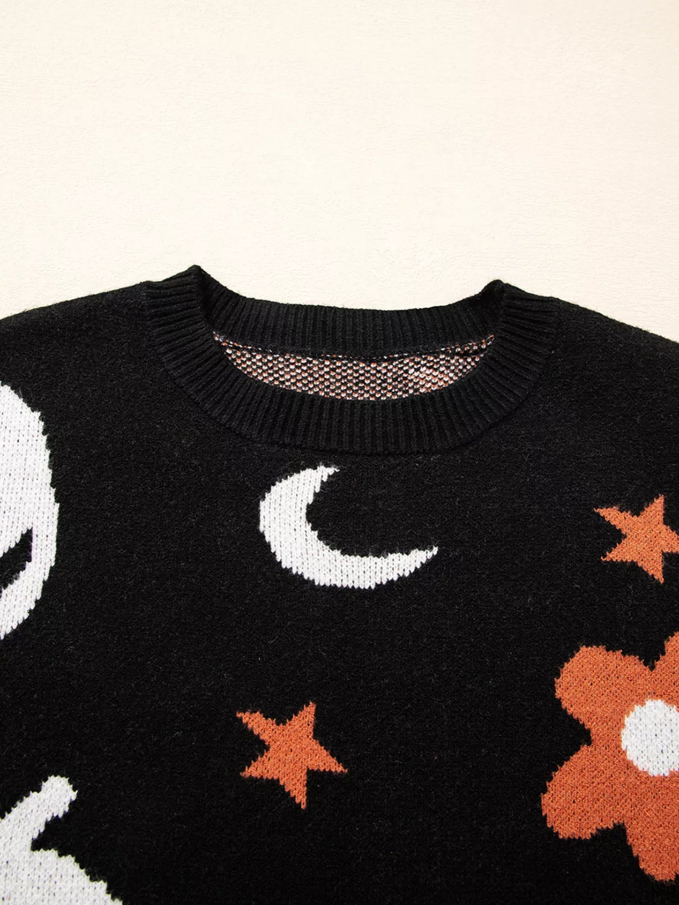 Black long sleeve sweater with white moons, orange stars, and orange flowers.
