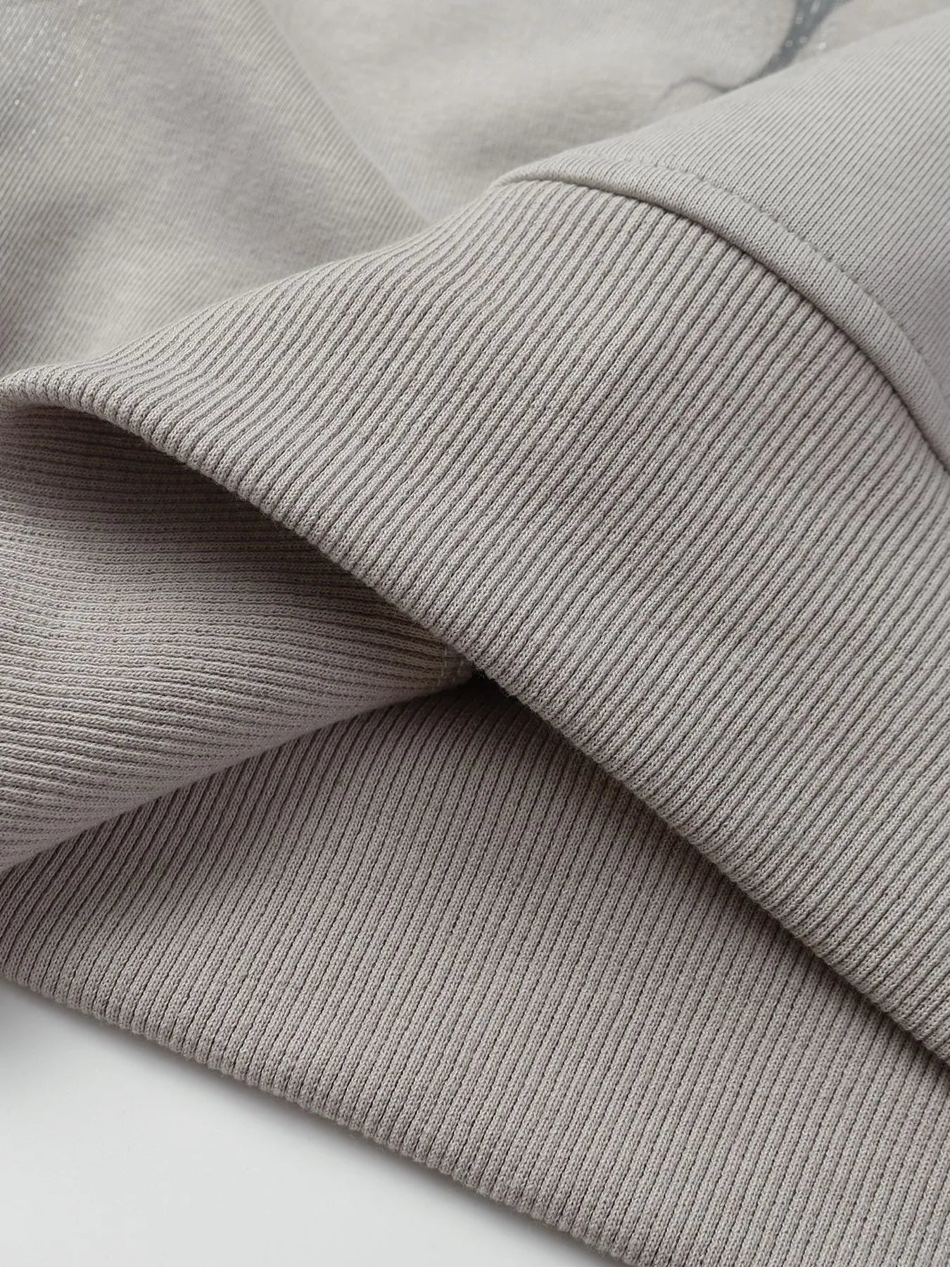Close-up of a light gray ribbed cuff and hem of a hoodie.