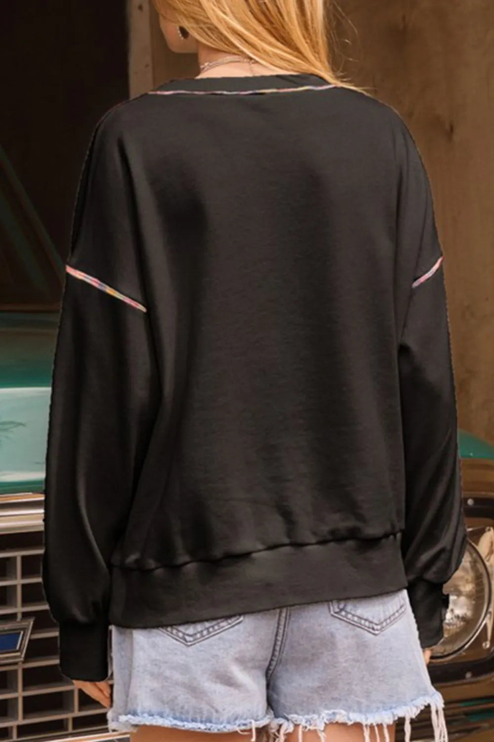 Black long-sleeve sweatshirt with colorful trim on the neckline and sleeves.
