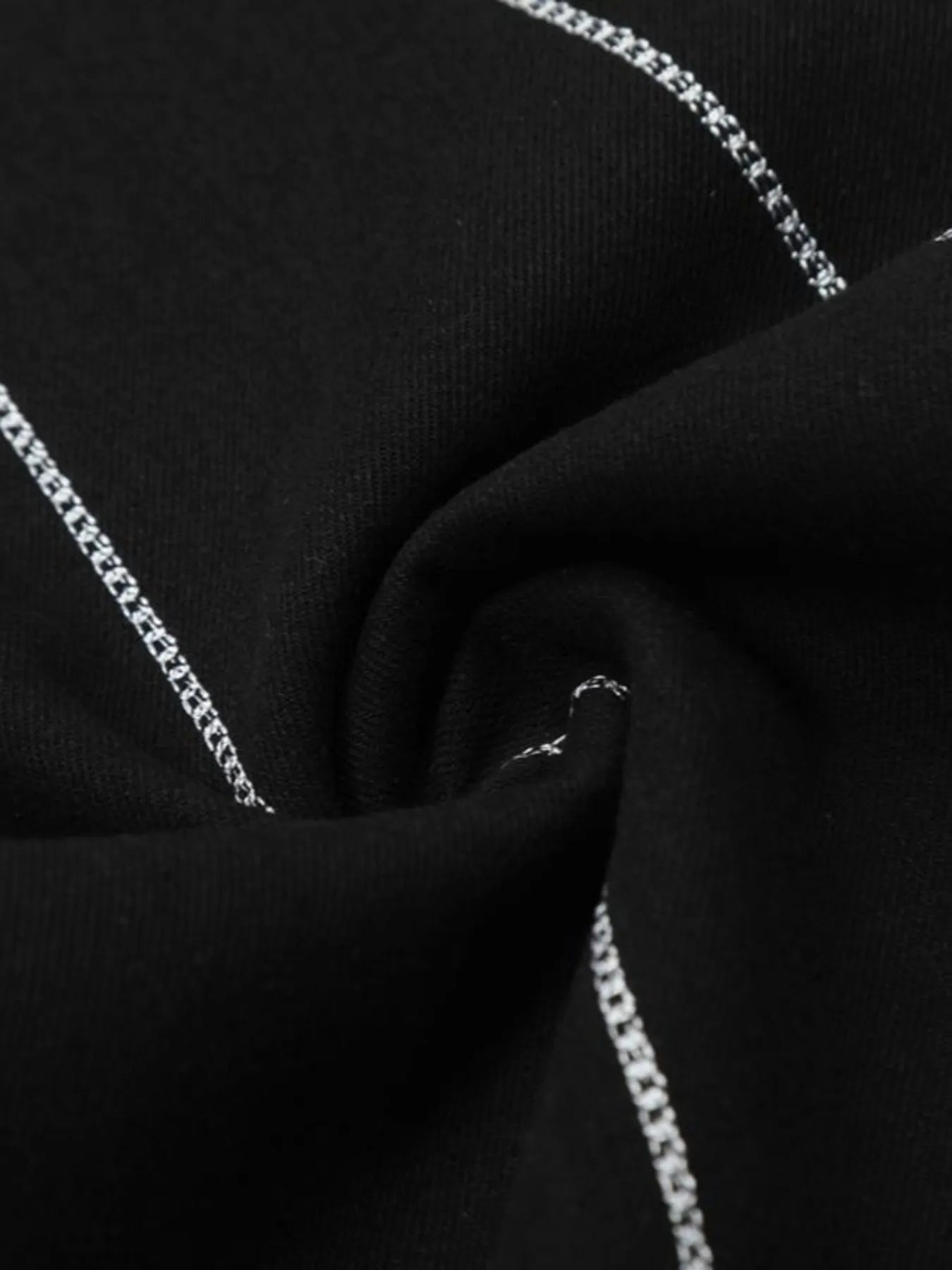 Close-up of black denim fabric with white chain-stitch embroidery.