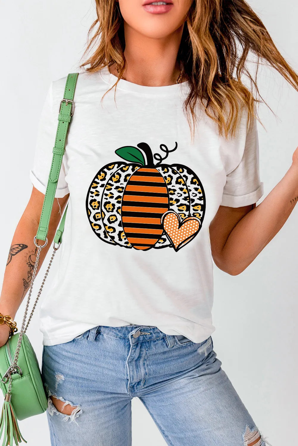 A woman wears a white short-sleeve t-shirt with a pumpkin graphic.