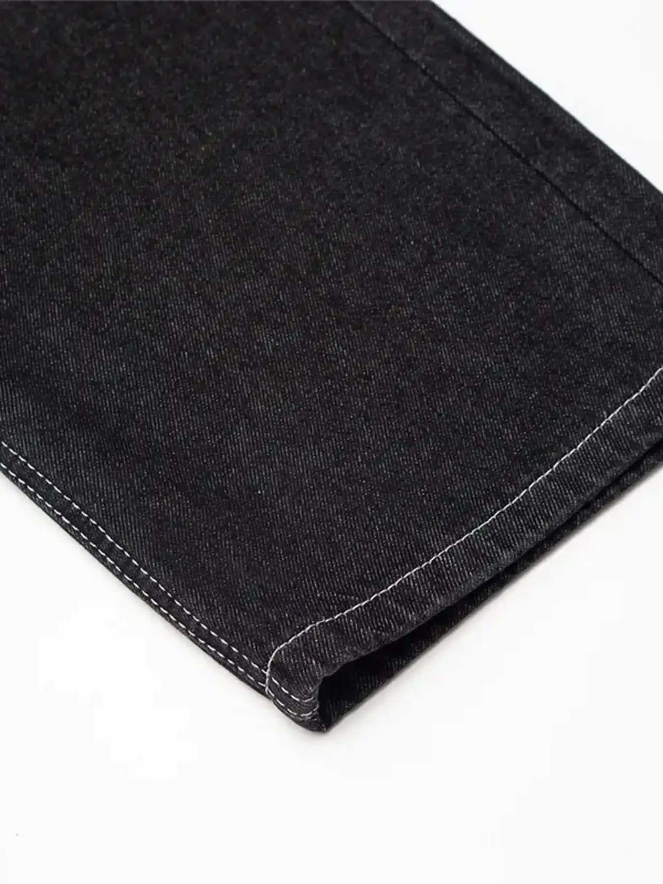 Close-up of black straight-leg jeans with white stitching on the hem.