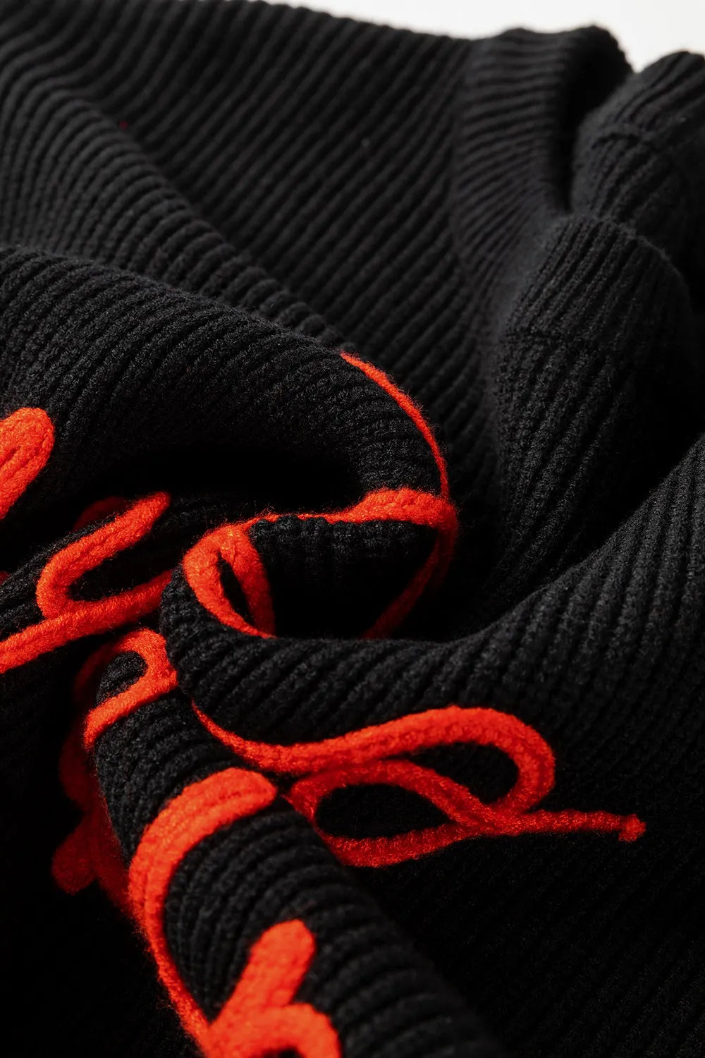 Black ribbed sweater with "HELLO PUMPKIN" embroidered in orange.