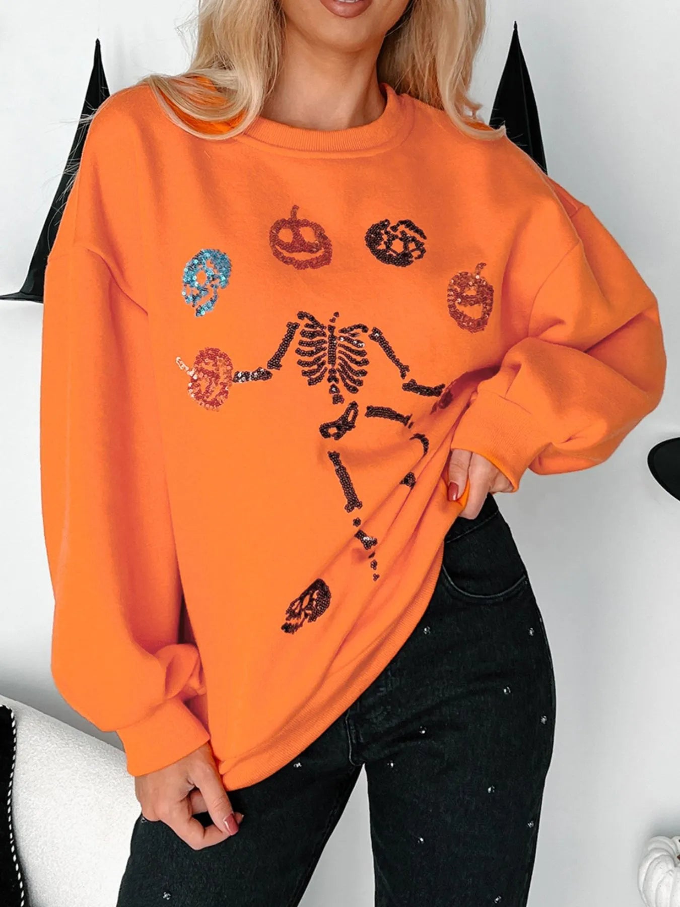 Orange Halloween sweatshirt with sequin skeleton and pumpkin designs.