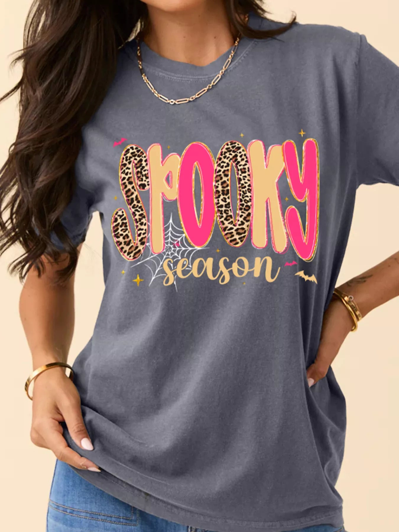 A woman wears a gray "Spooky Season" graphic t-shirt with leopard print letters.