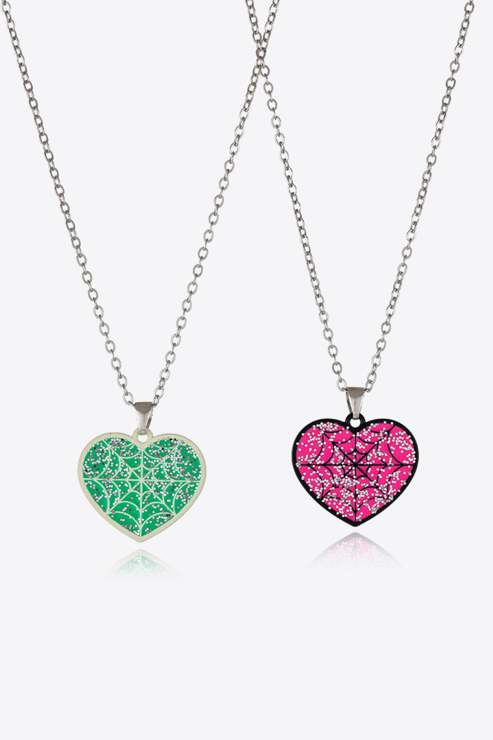 Two heart-shaped necklaces, one green and one pink, with spiderweb designs.