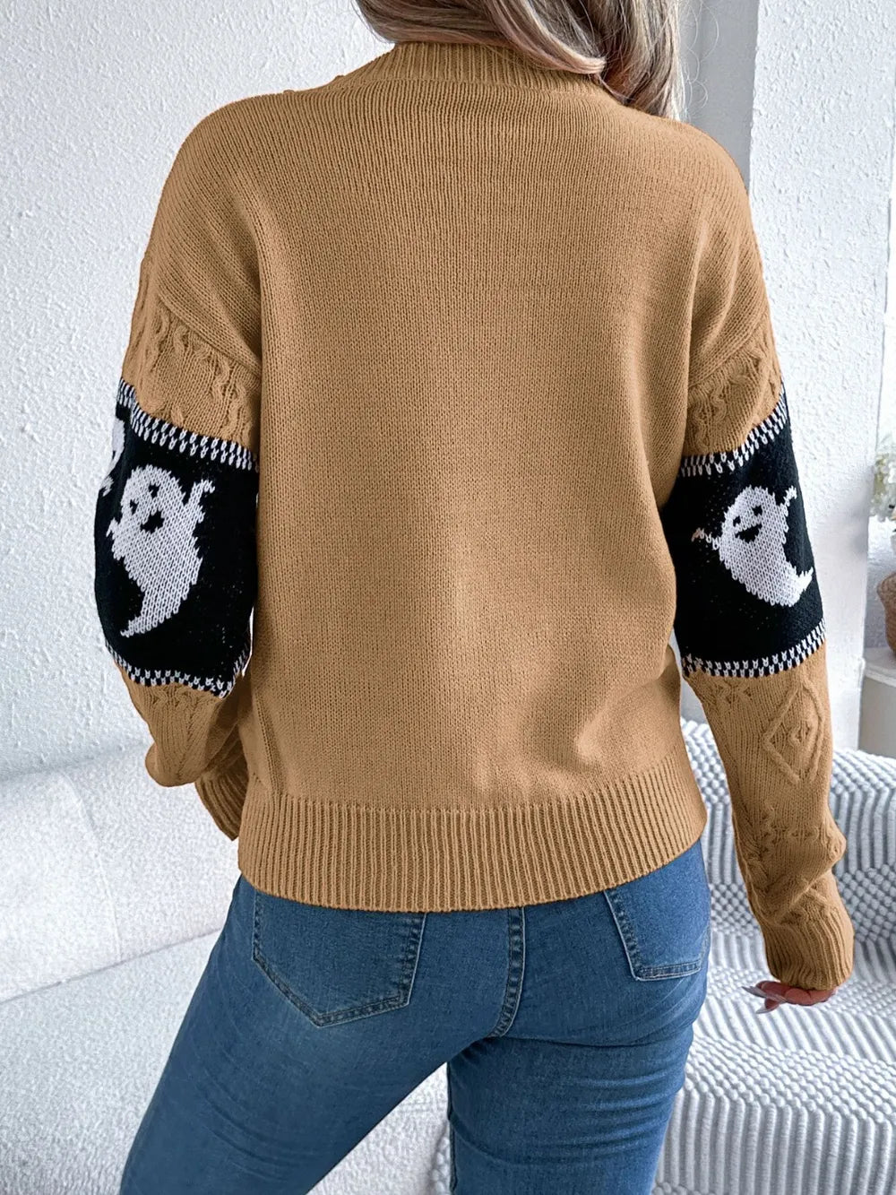 A woman from behind wears a tan long-sleeve sweater with black and white ghost sleeves.