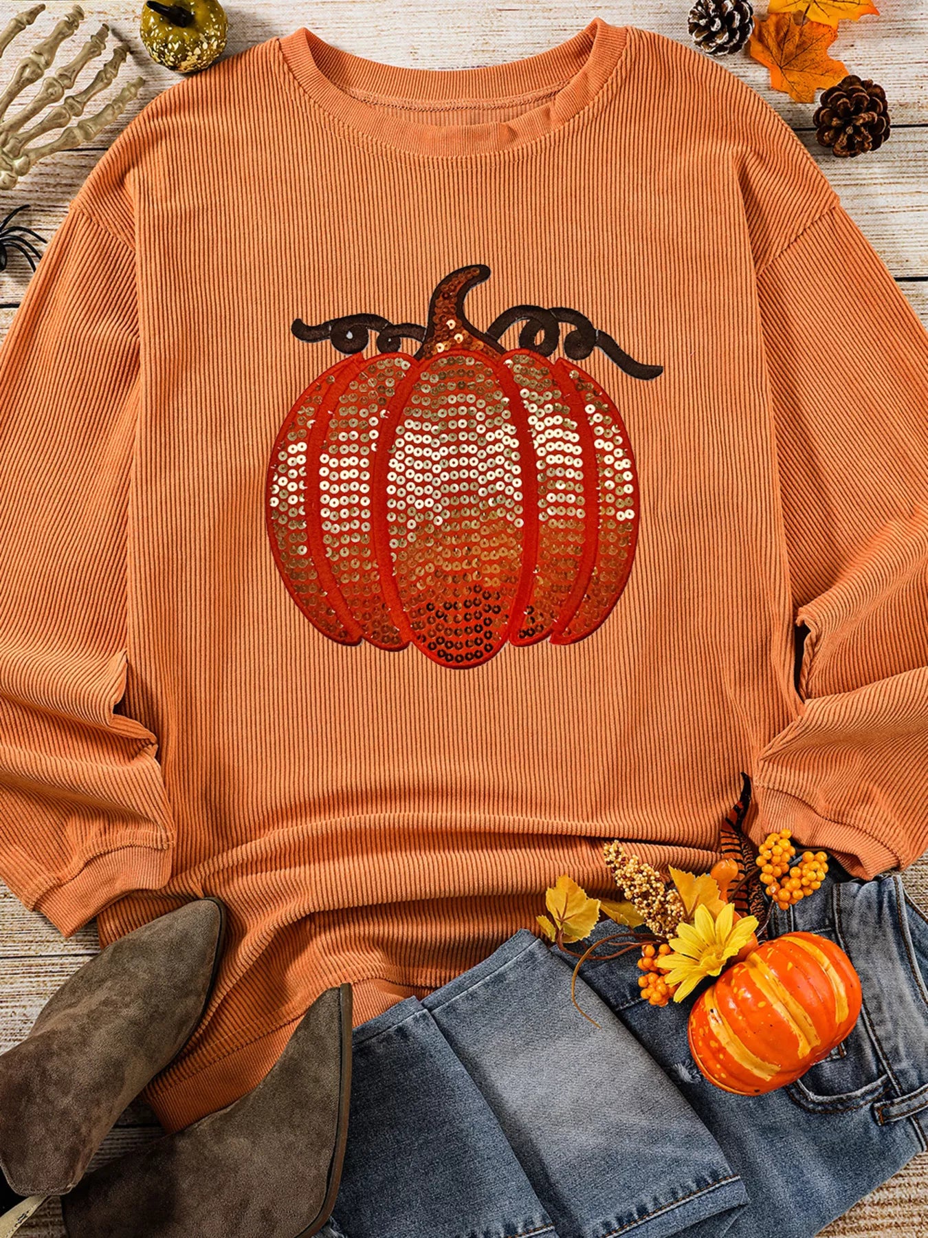 Orange ribbed sweatshirt with a sequined pumpkin design.