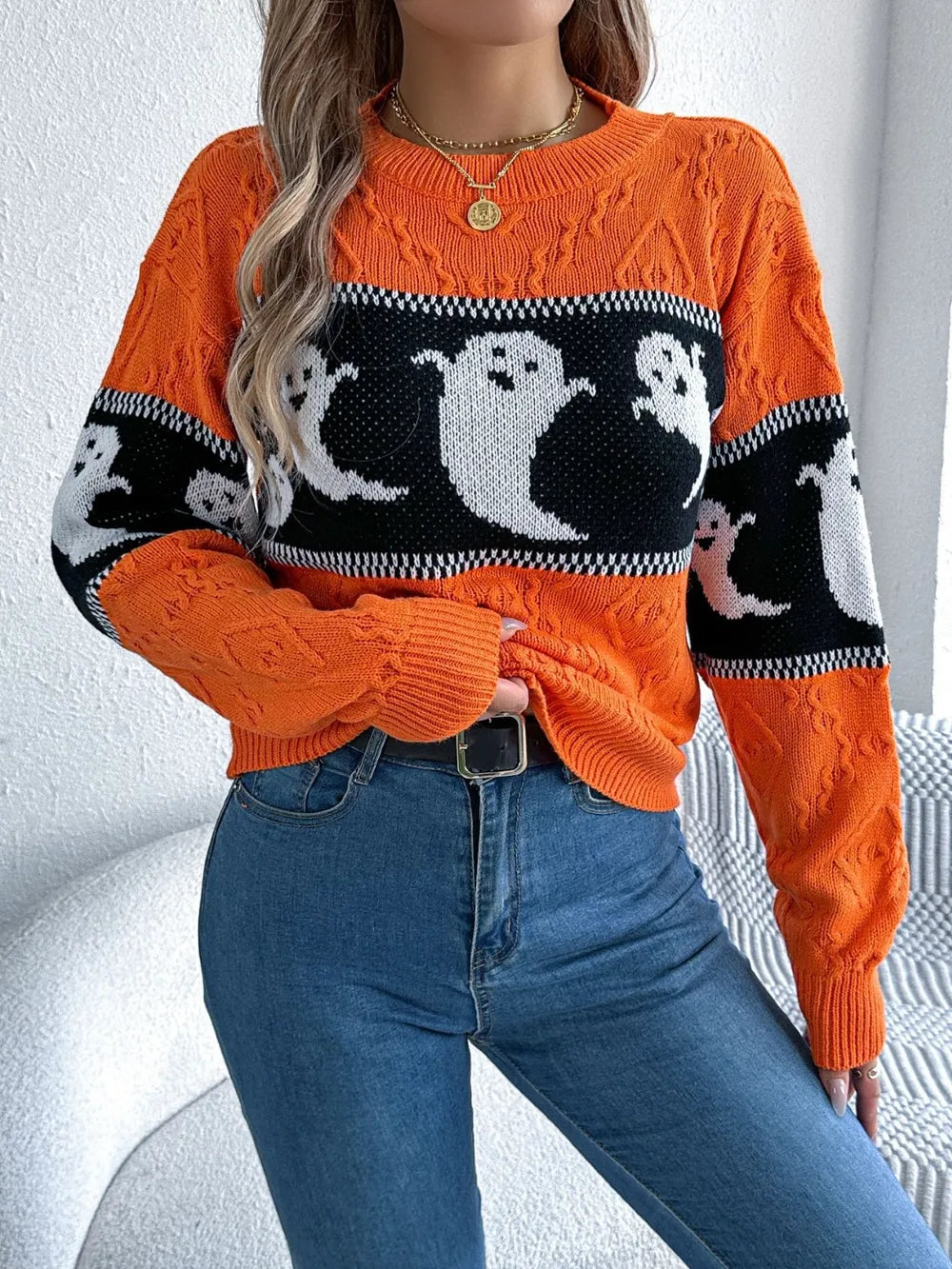 Orange long-sleeve sweater with a black and white ghost pattern.