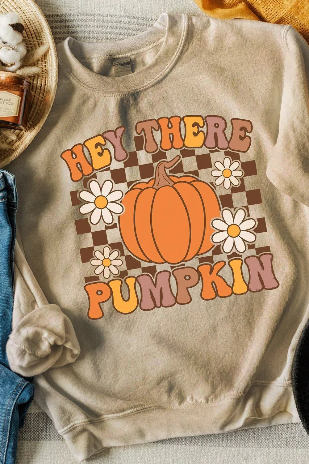 A beige long-sleeve sweatshirt with a "Hey There Pumpkin" graphic and checkered background.