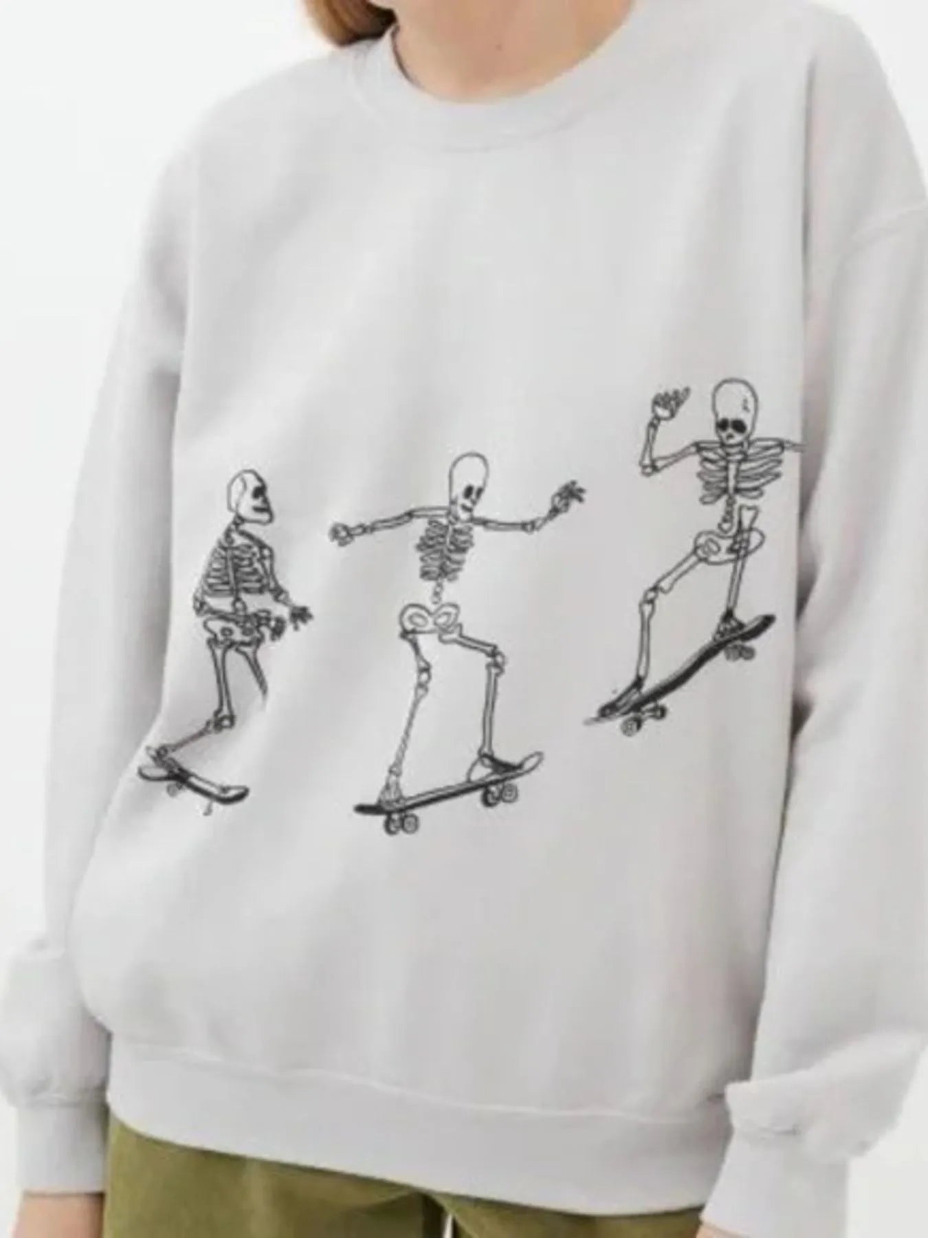 Oversized sweatshirt with three skeleton figures skateboarding across the front.