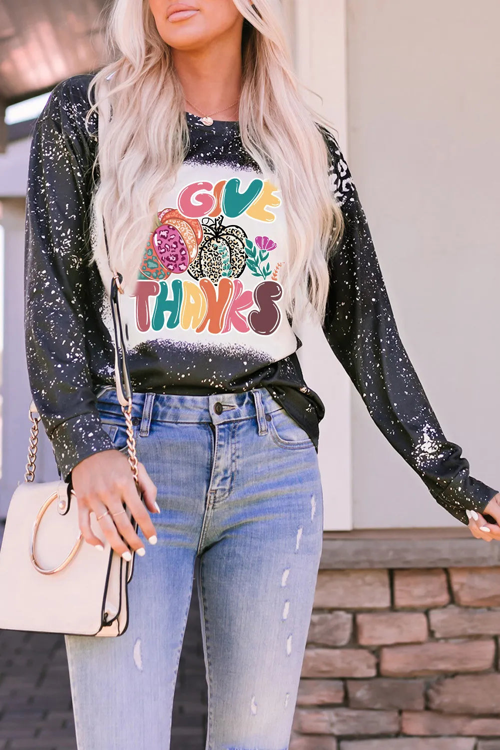 A woman wears a black long-sleeve t-shirt with a "Give Thanks" pumpkin graphic.