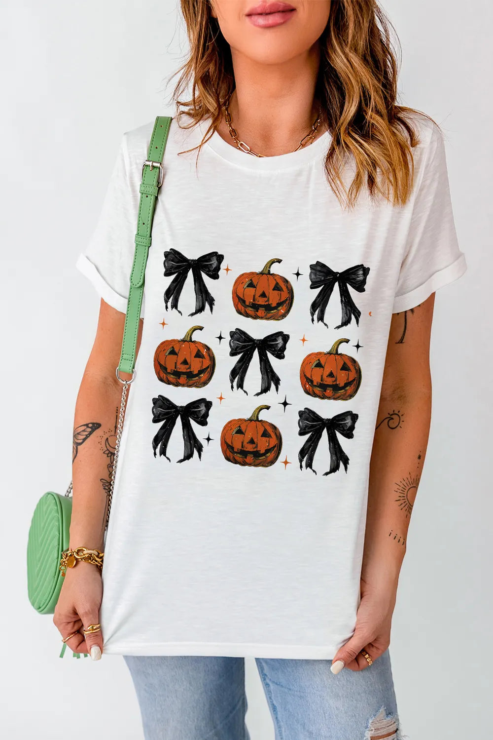 A woman wears a white short-sleeve t-shirt with a pumpkin and bow pattern.