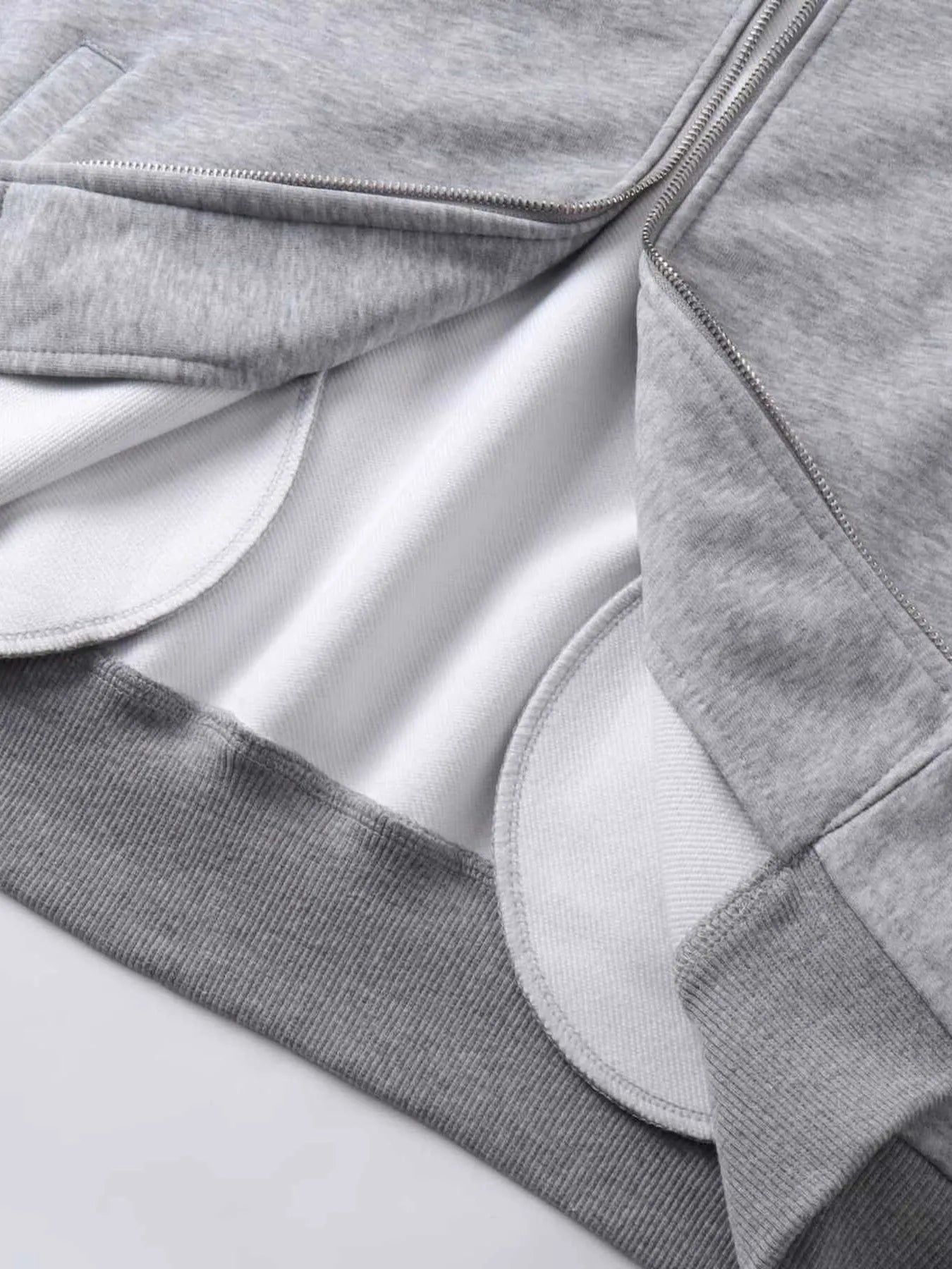 Gray zip-up hoodie with white lining and ribbed hem.