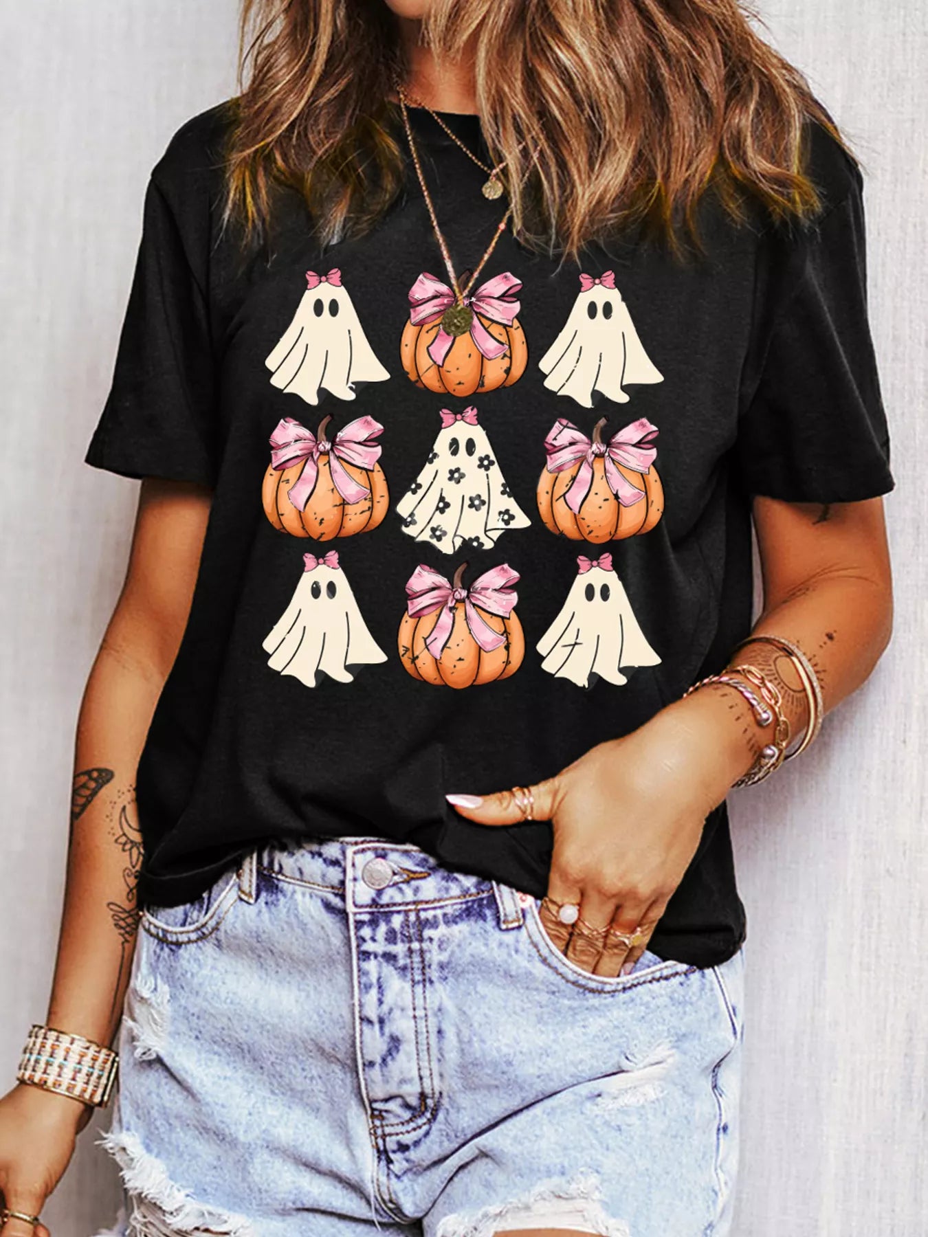 Black t-shirt with a Halloween graphic of ghosts and pumpkins with pink bows.