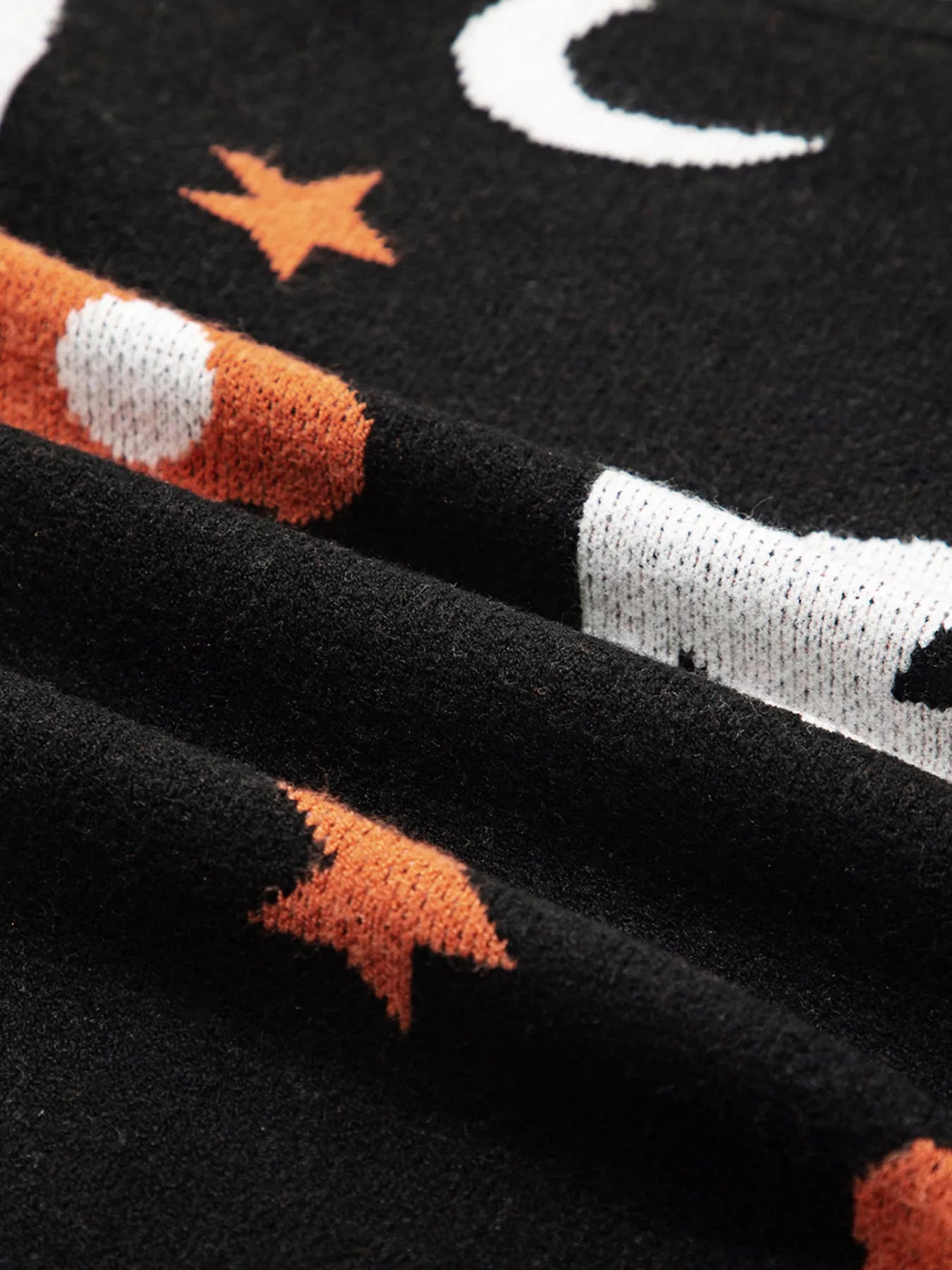 Black long-sleeve sweater with white crescent moons and orange stars.