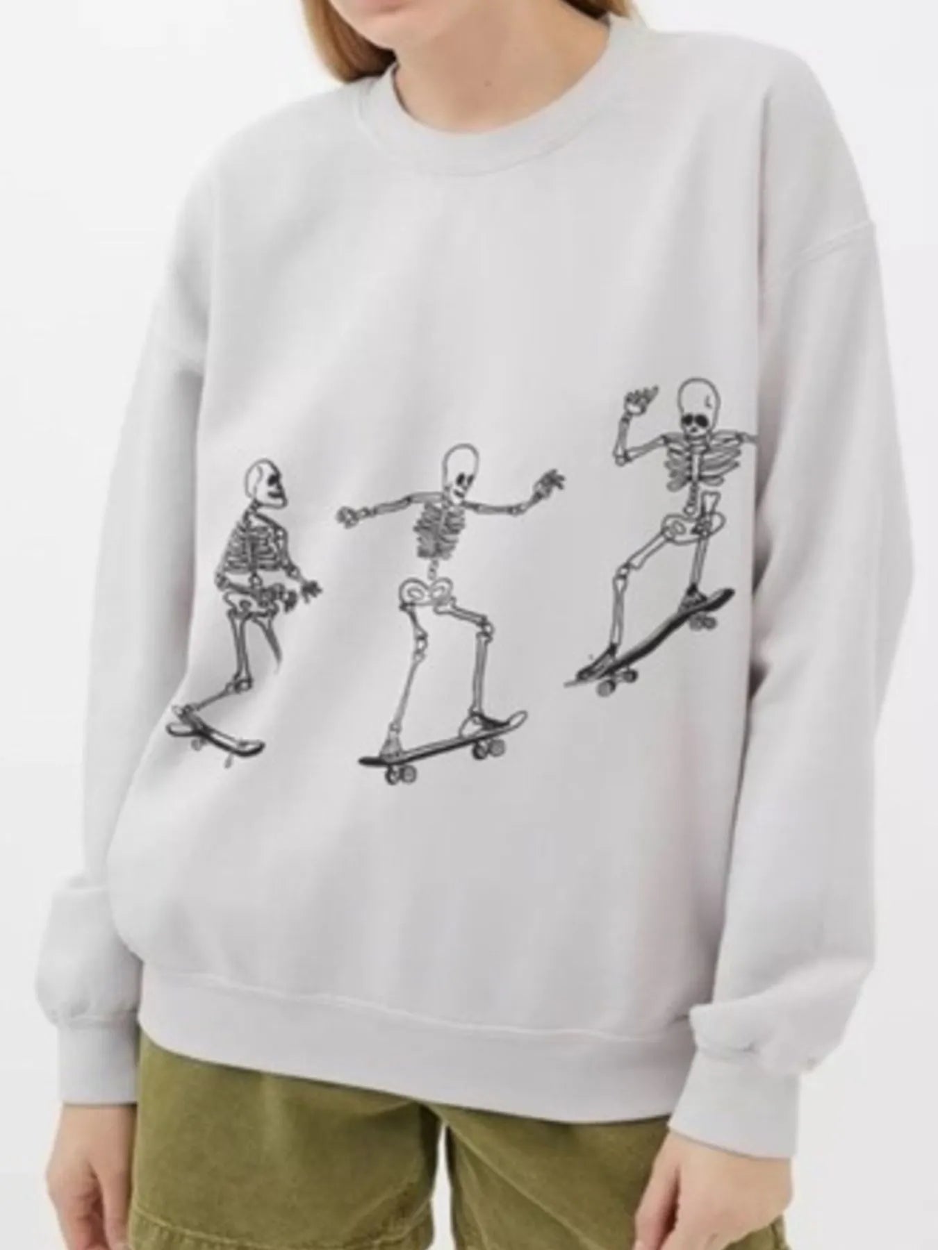 An oversized sweatshirt with three skateboarding skeletons.