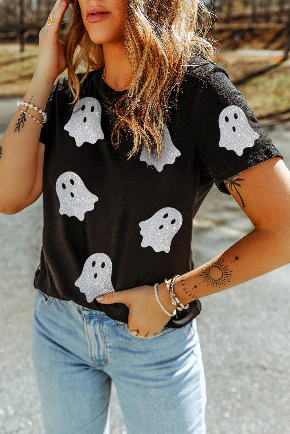 A woman wears a black short-sleeve t-shirt with glitter ghost graphics.