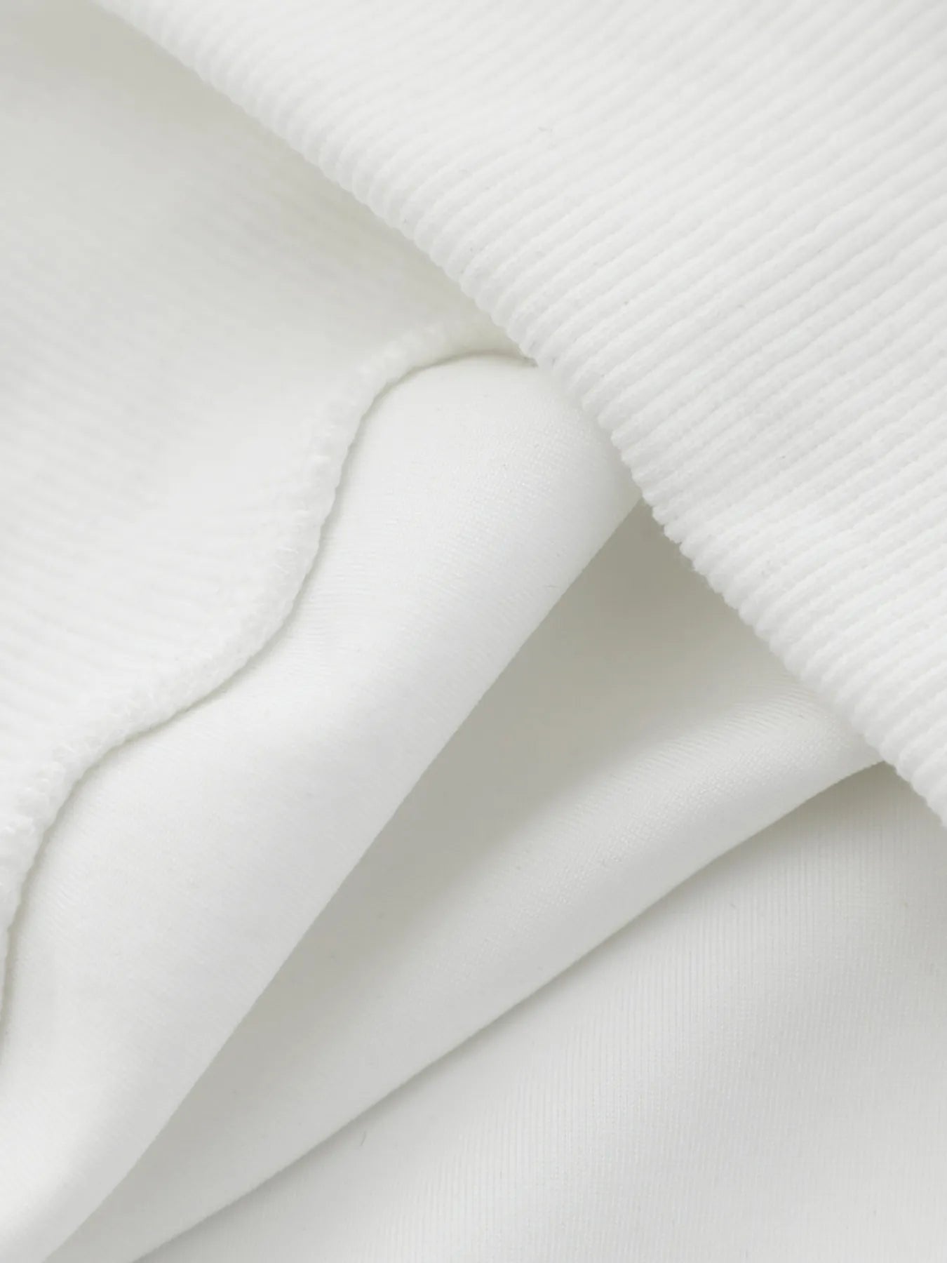 A close-up of the white ribbed and smooth fabric of the hoodie.