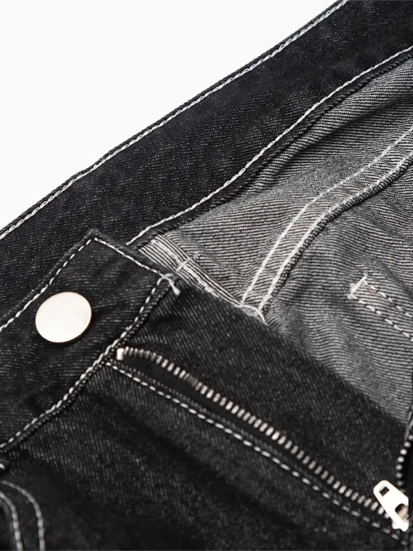 Close-up of black denim jeans with white stitching, a silver button, and a zipper.