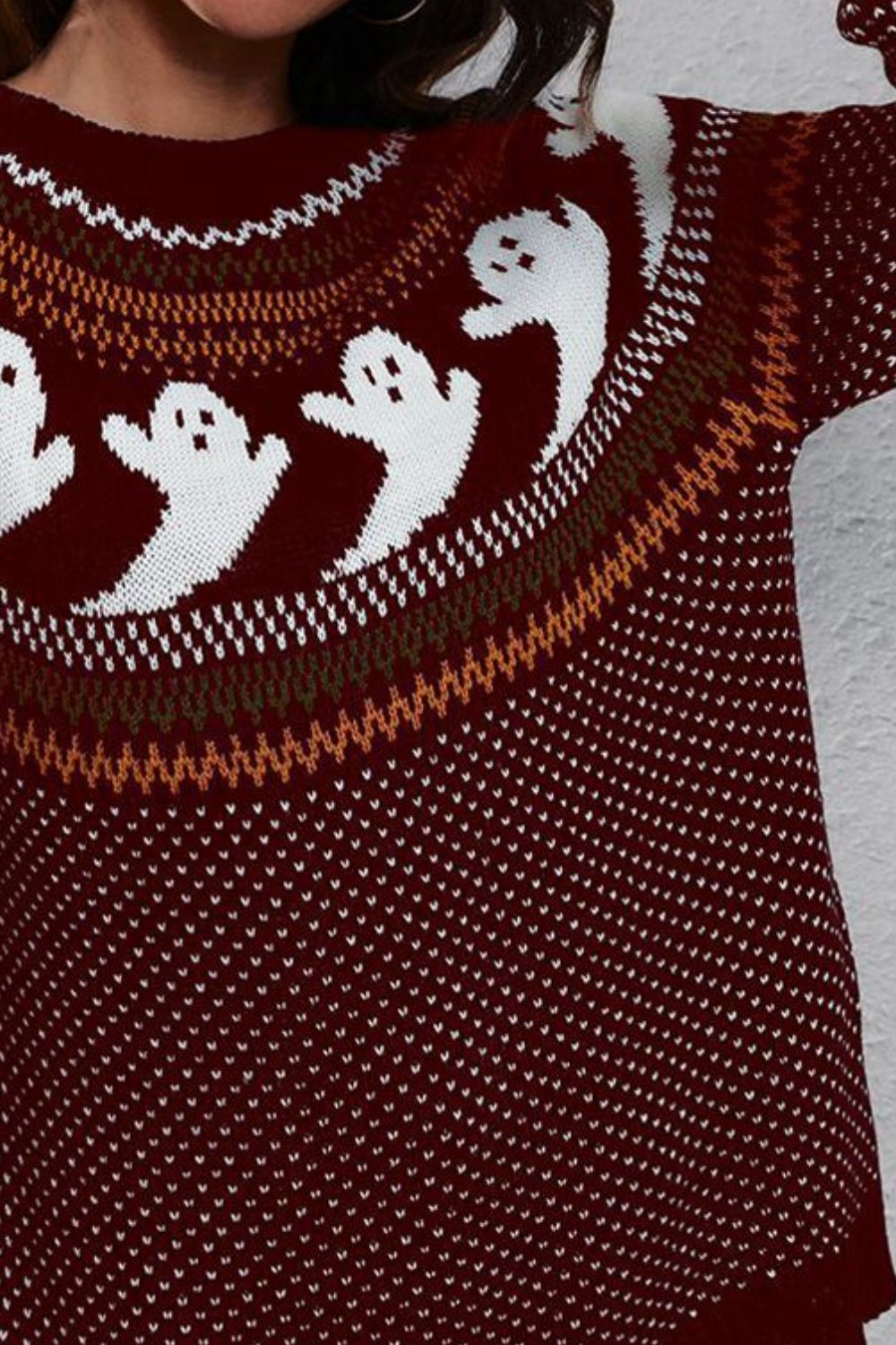 A maroon long-sleeve sweater with white ghost patterns and colorful trim.