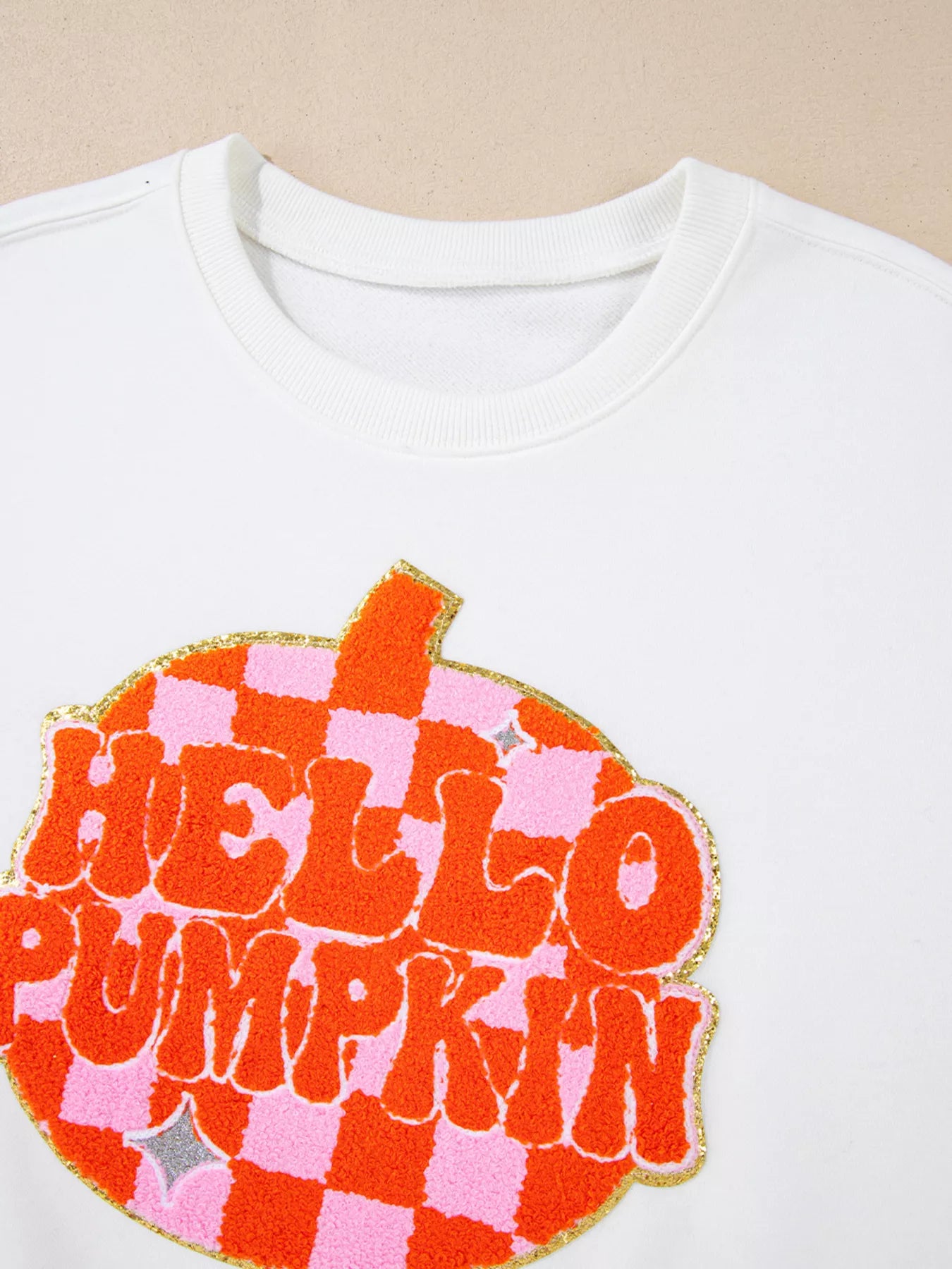 White long-sleeve sweatshirt with a large orange and pink checkered "Hello Pumpkin" patch.