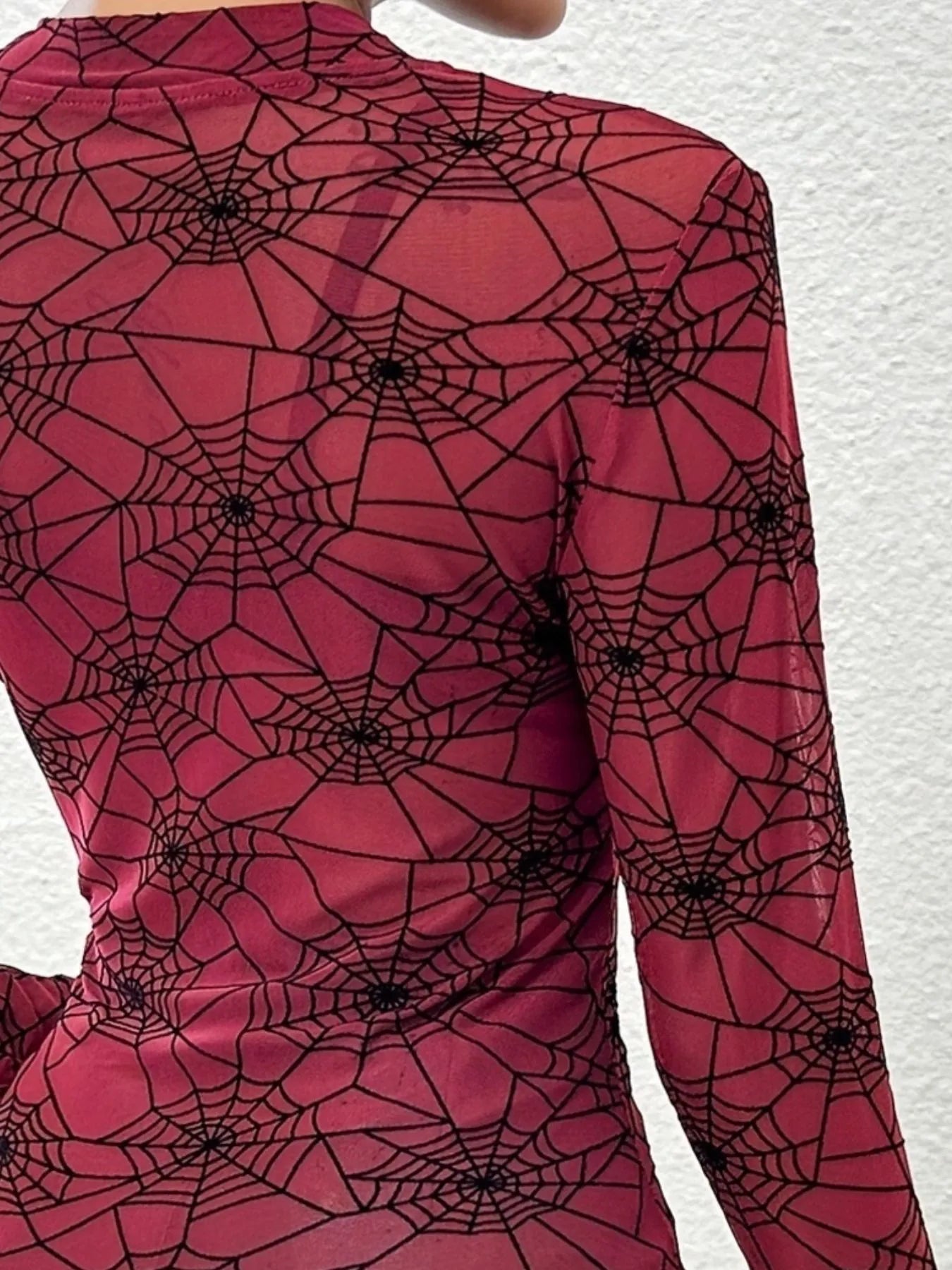 A sheer, long-sleeve blouse in red with a black spider web print.