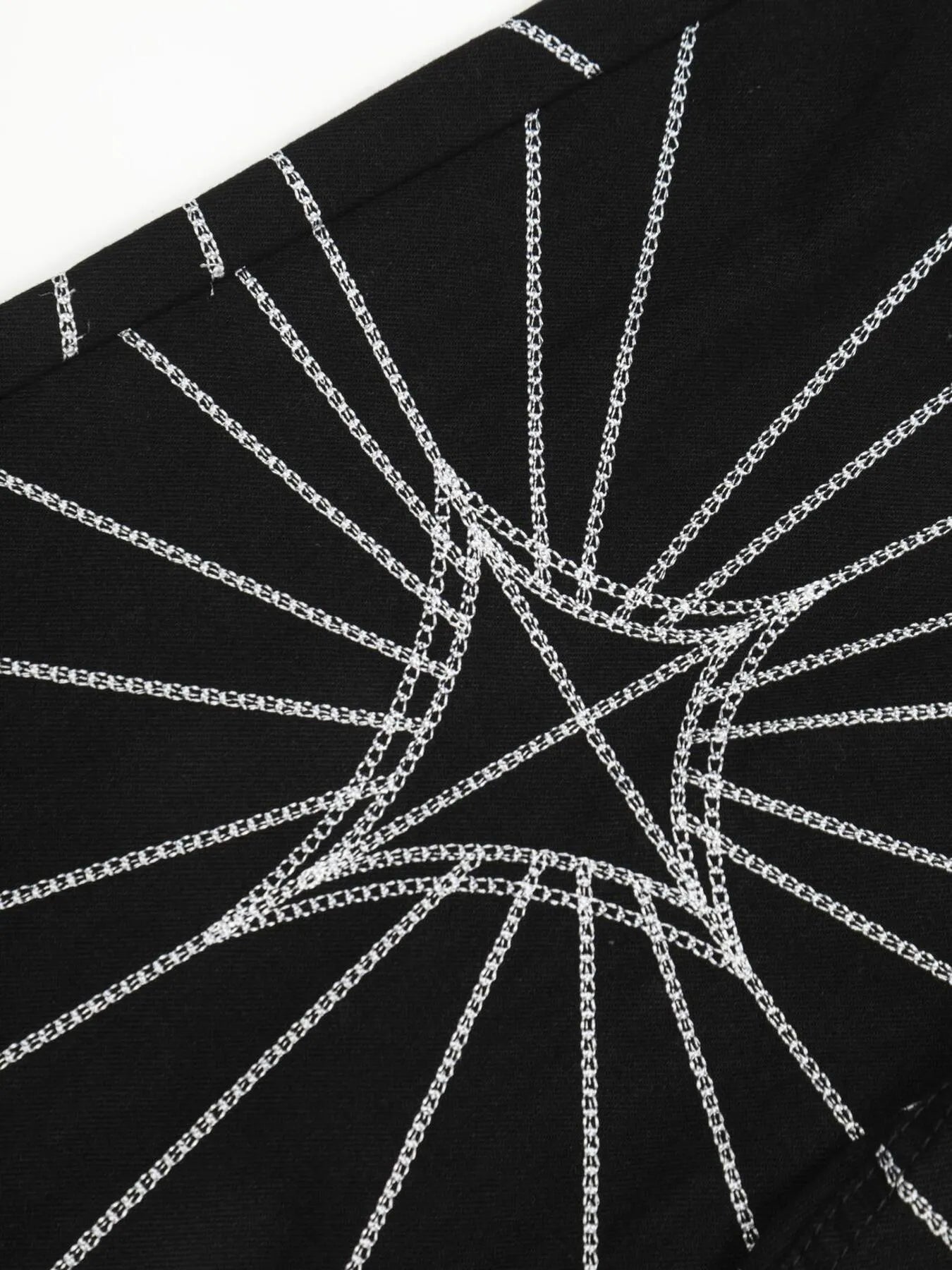 Black jeans with white spider web embroidery.