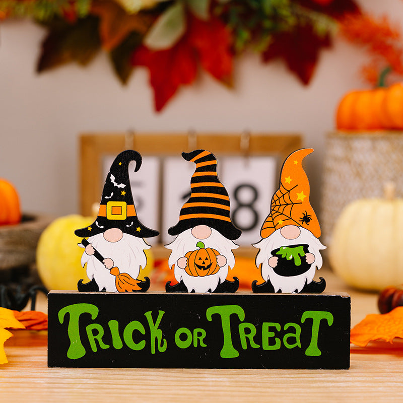 Three Halloween gnome ornaments stand on a black "Trick or Treat" sign.