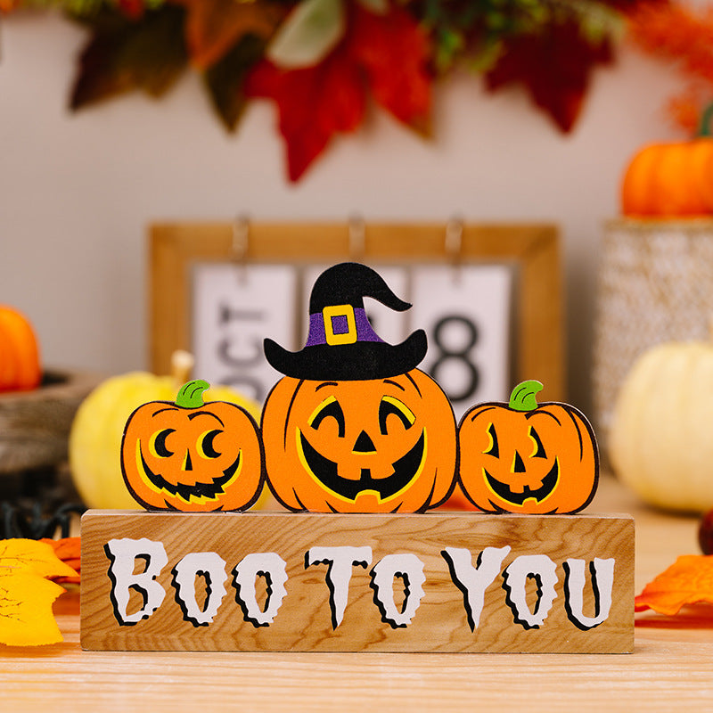 Three Halloween pumpkin ornaments on a wooden block that reads "BOO TO YOU."