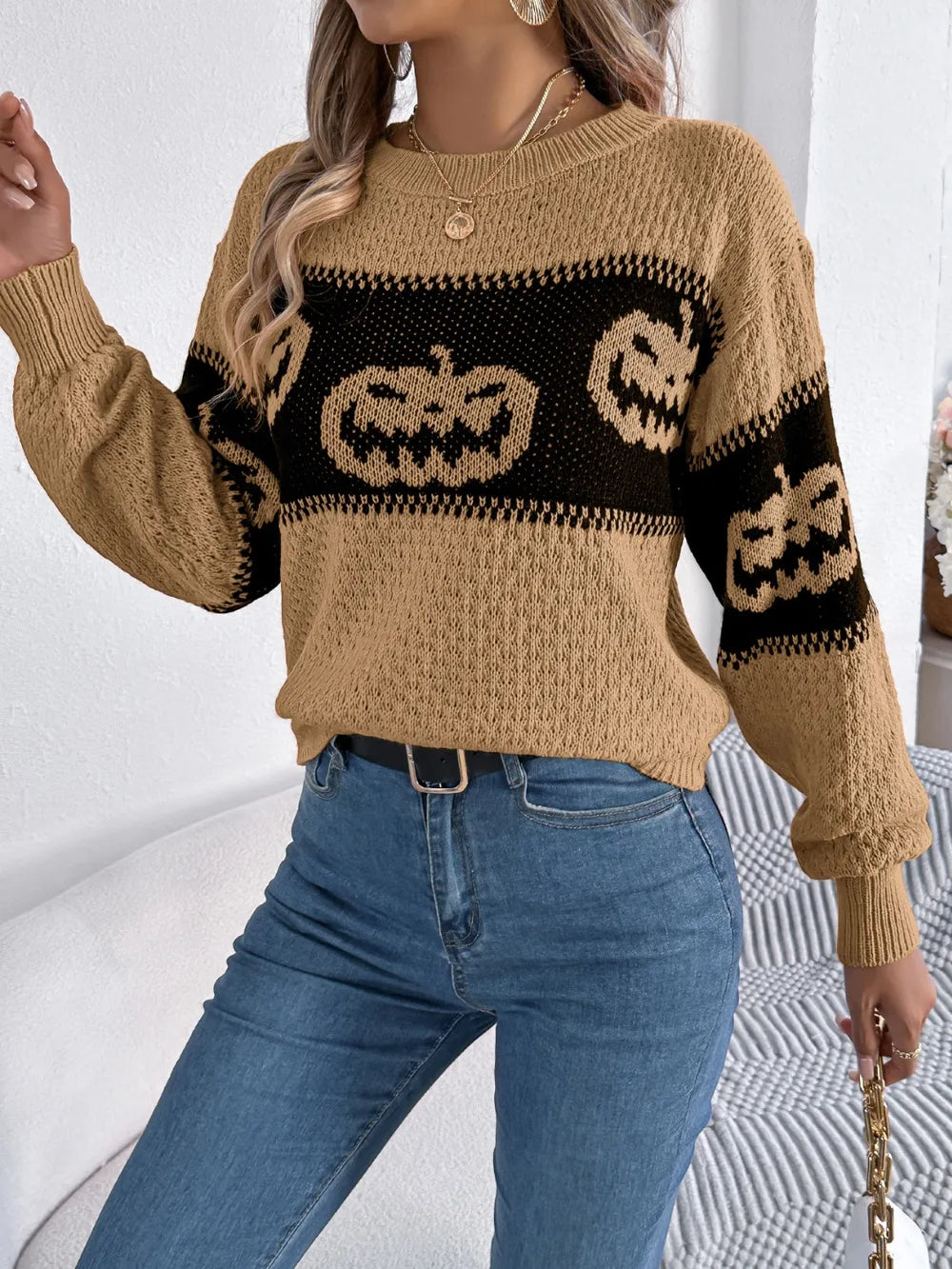 A woman wears a pumpkin round neck long sleeve sweater with blue jeans.