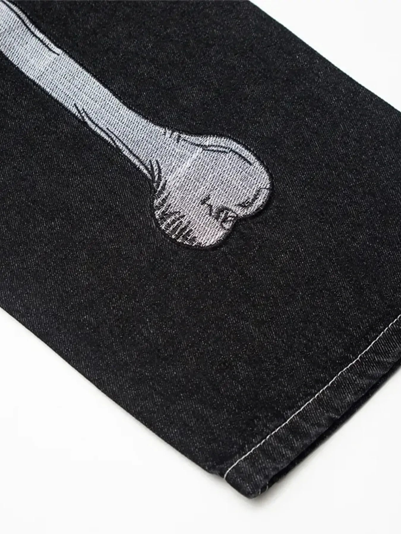 Black straight-leg jeans with a gray embroidered bone design.